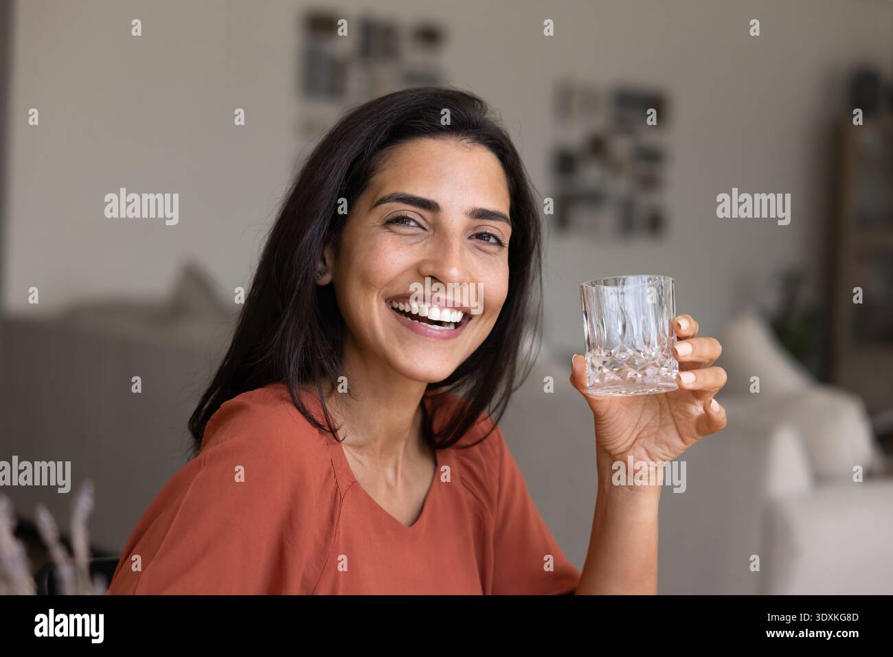 Portrait d'une femme regardant la caméra, tenant un verre d'eau Banque D'Images