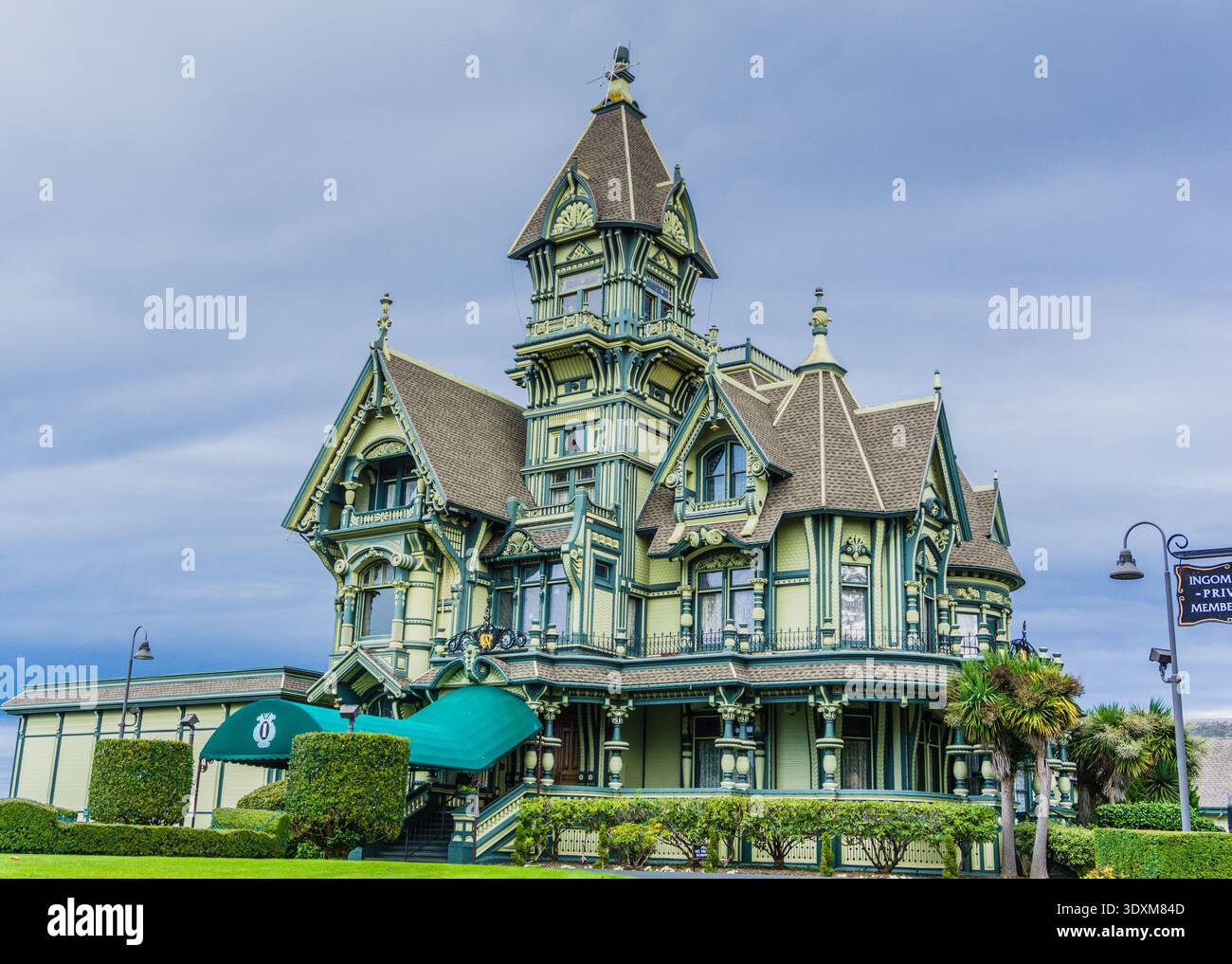 Une grande maison ancienne avec un auvent vert et un panneau sur le devant. La maison est entourée d'une pelouse verte luxuriante et a beaucoup d'arbres en arrière-plan Banque D'Images