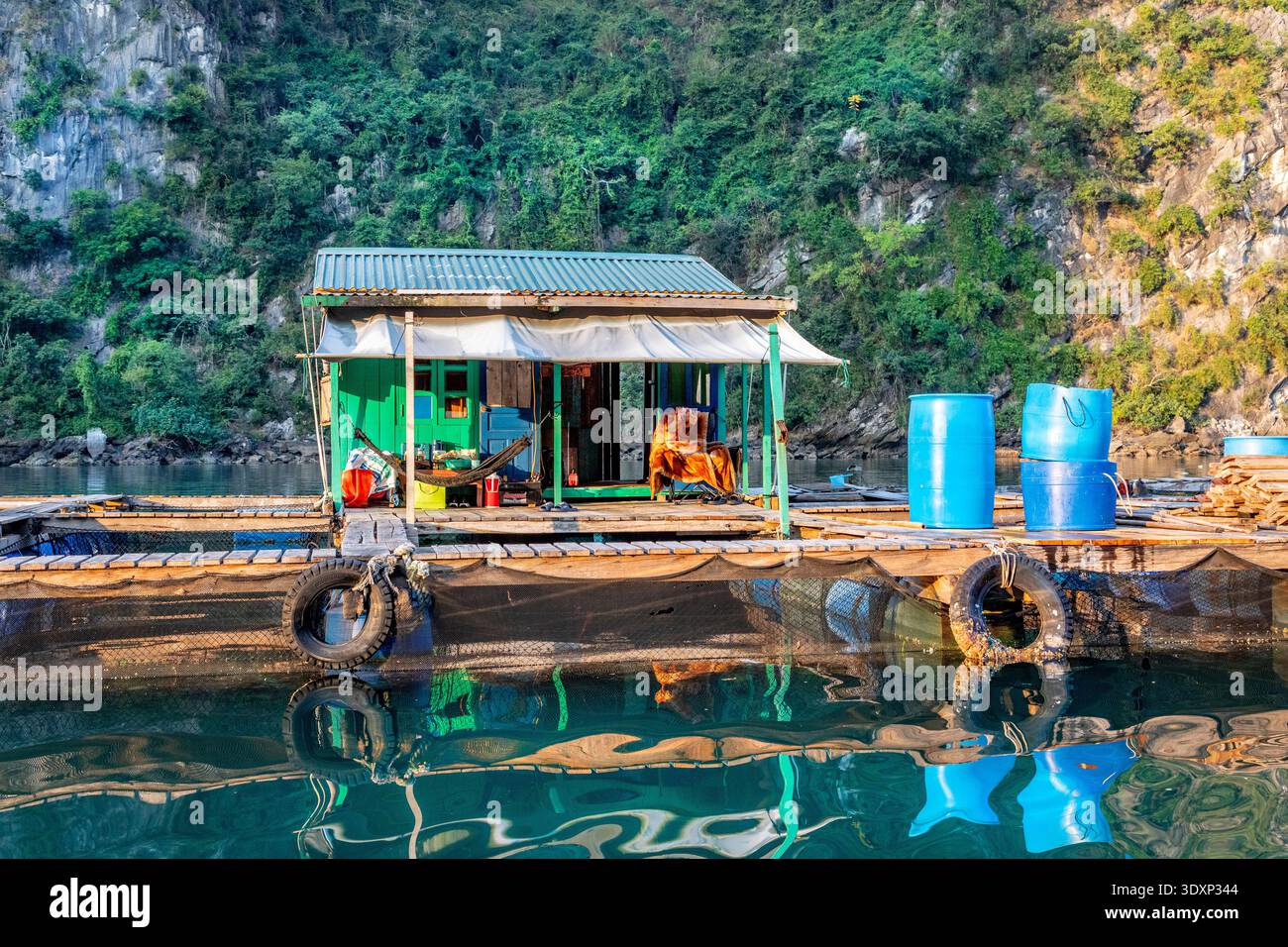 Une petite maison flottante dans une ferme piscicole dans la baie d'Ha long, au Vietnam. Banque D'Images