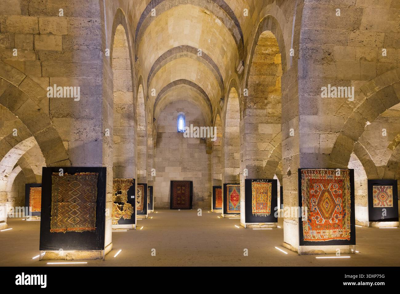 Grand hall en pierre avec des tapis illuminés entre des arches imposantes, caravansérail Sultanhani, sur l'ancienne route de la soie, musée, SultanhanIJ Kervansaray, Banque D'Images