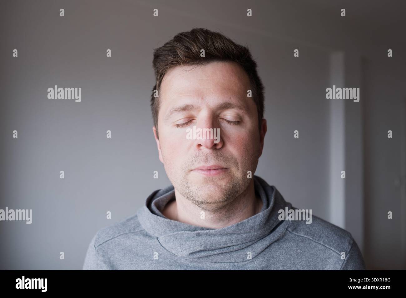 Serein homme caucasien d'âge moyen debout avec les yeux fermés, profitant d'un moment paisible Banque D'Images