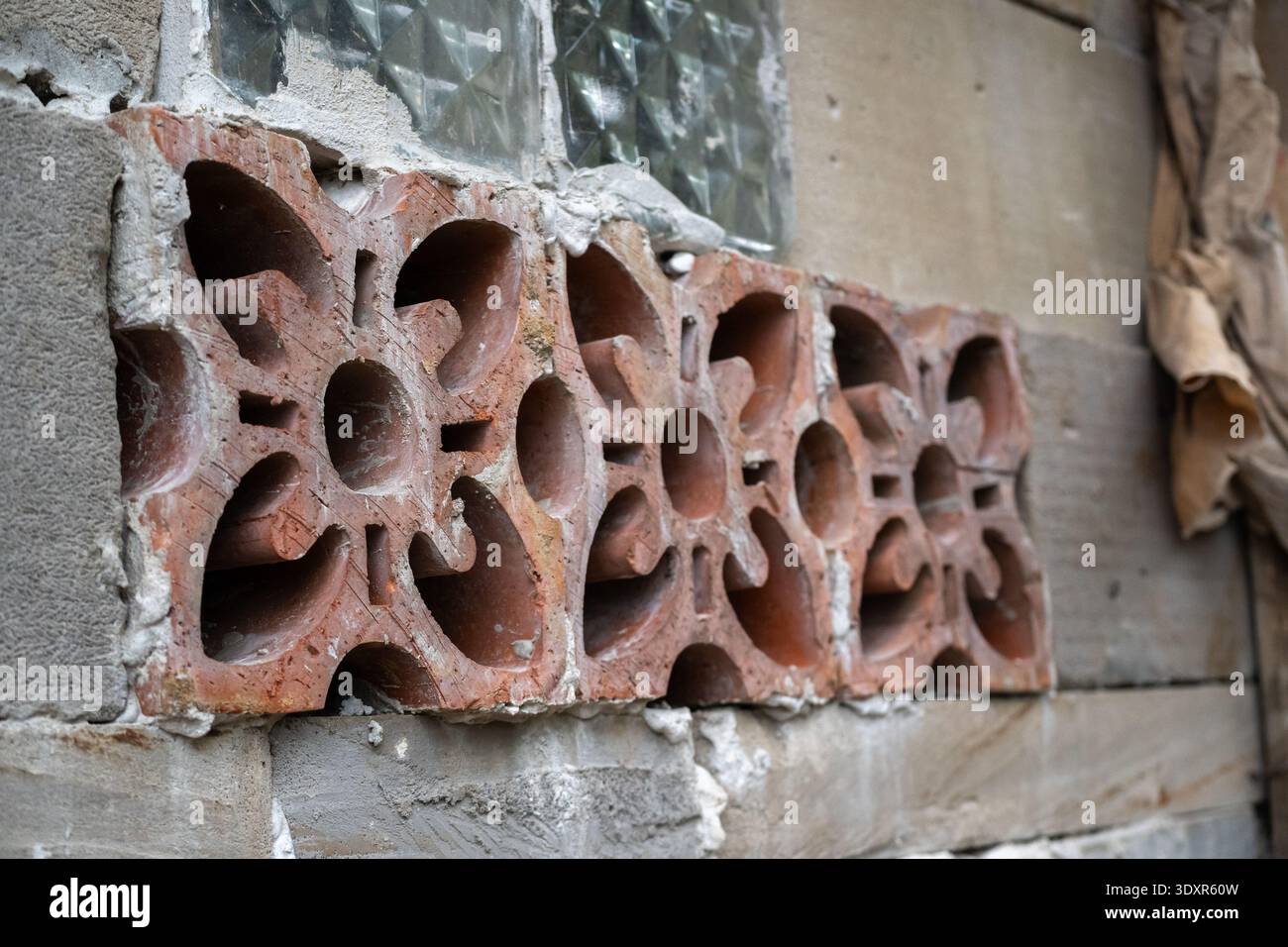 Bloc de ventilation en argile rouge dans un mur en béton gris Banque D'Images