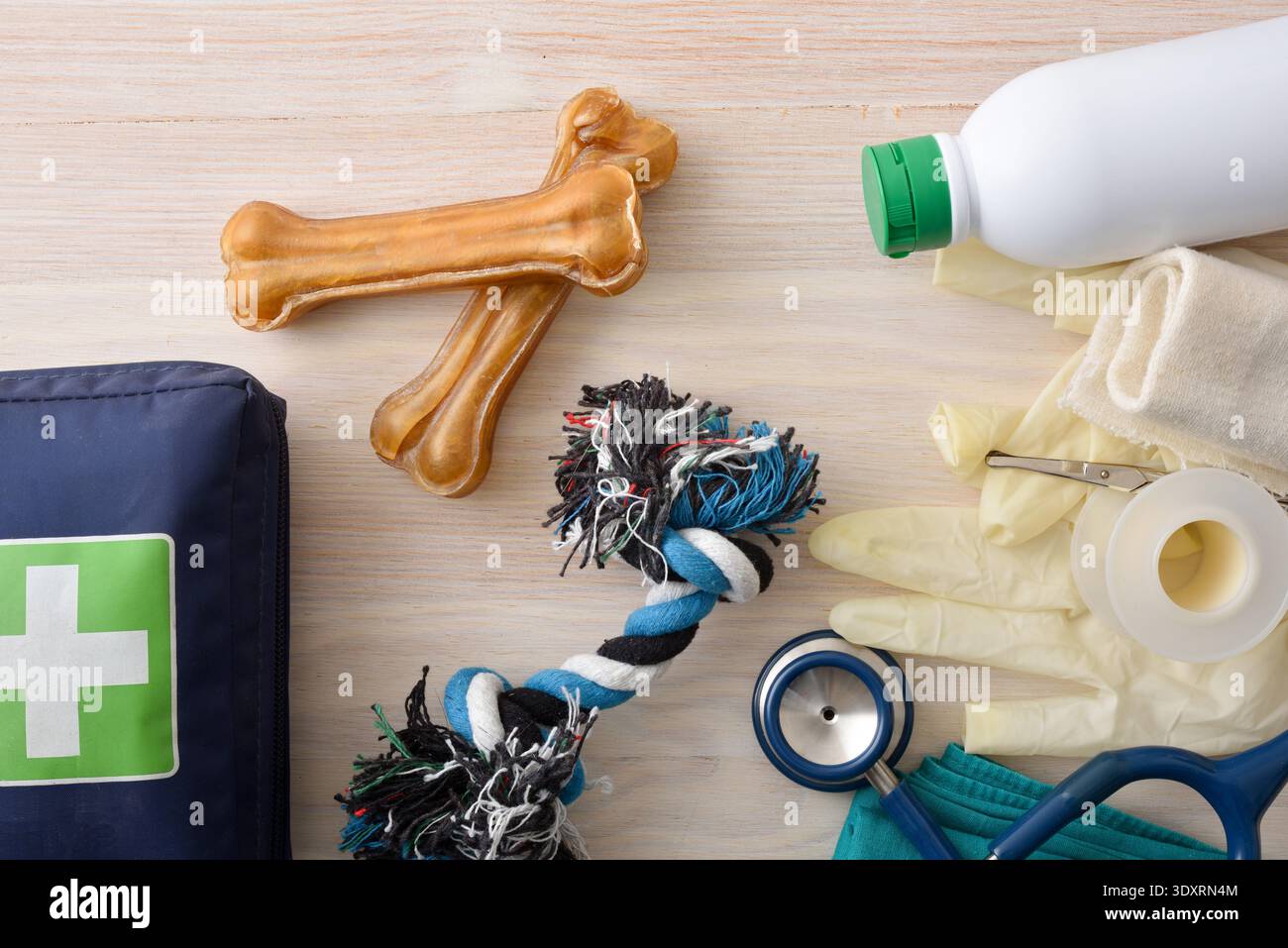 Vue de dessus des fournitures de premiers soins pour chiens avec bandages, gants, désinfectant, stéthoscope et jouets à mâcher sur une table en bois, concept de soins d'urgence pour animaux de compagnie et Banque D'Images