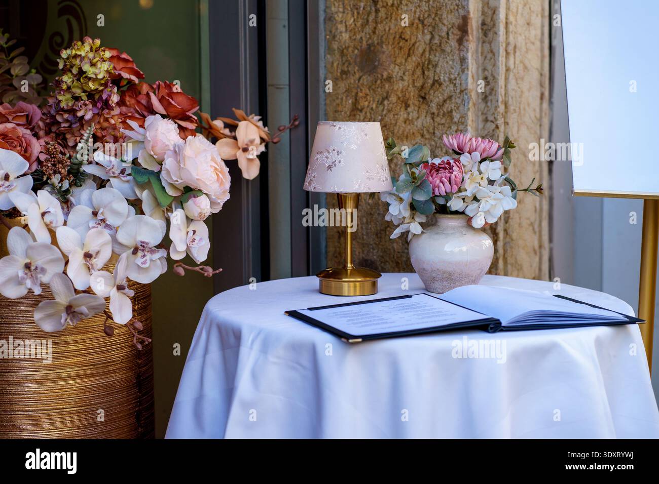 Table de café décorée avec arrangement floral et menu. Concept de cuisine fine, configuration de réception de mariage et thème élégant de l'hospitalité. Banque D'Images