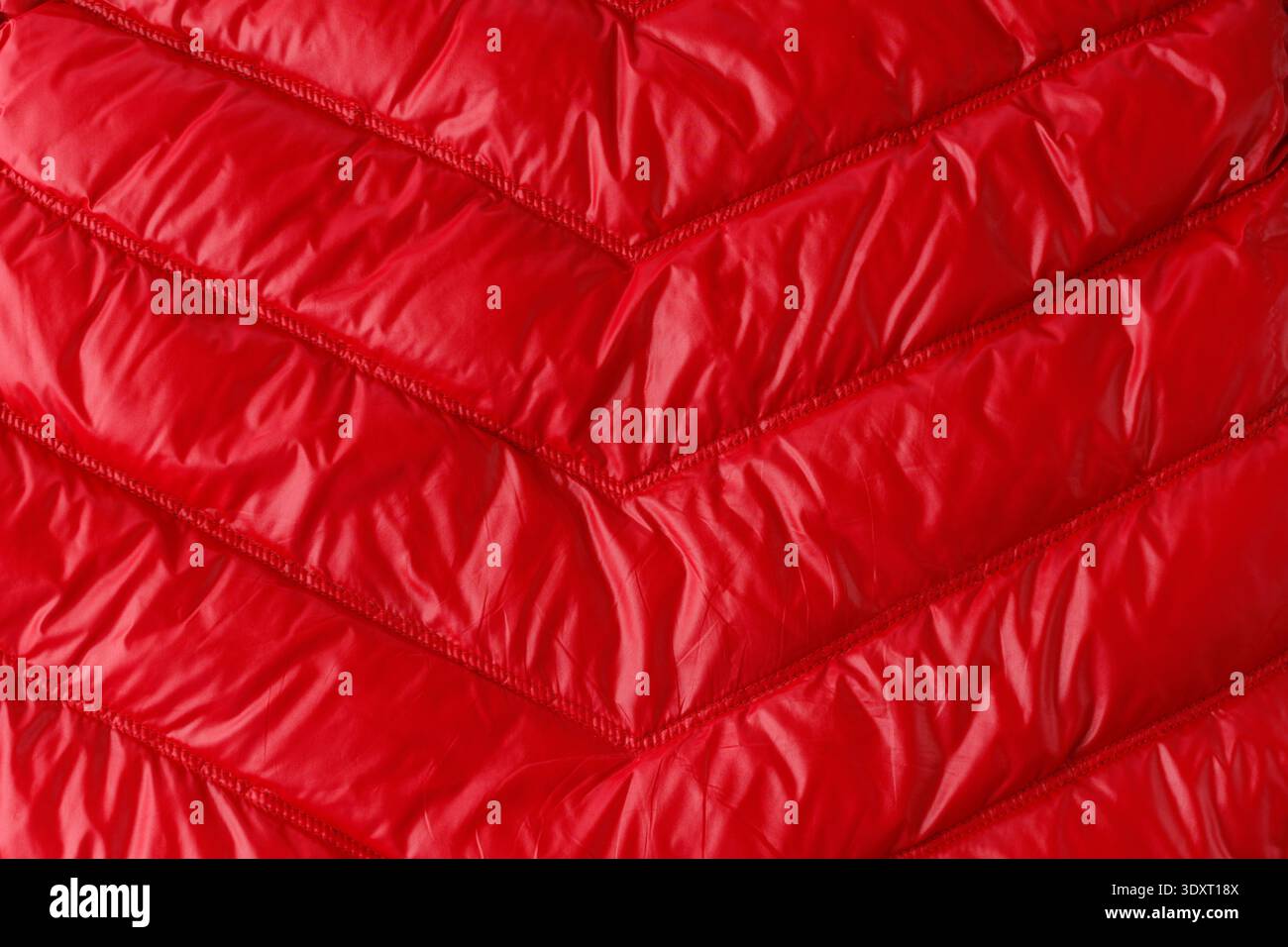 Texture de veste ou manteau en duvet rouge matelassé comme fond. Détail des vêtements d'hiver. Banque D'Images