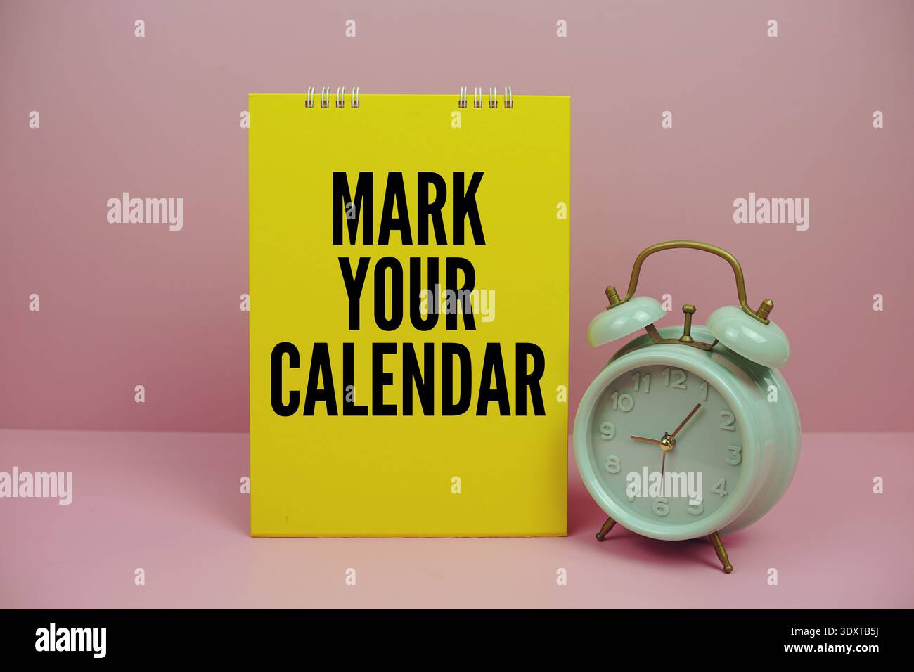 Message de motivation 'Mark Your Calendar' avec réveil vintage vert, sur fond rose Banque D'Images