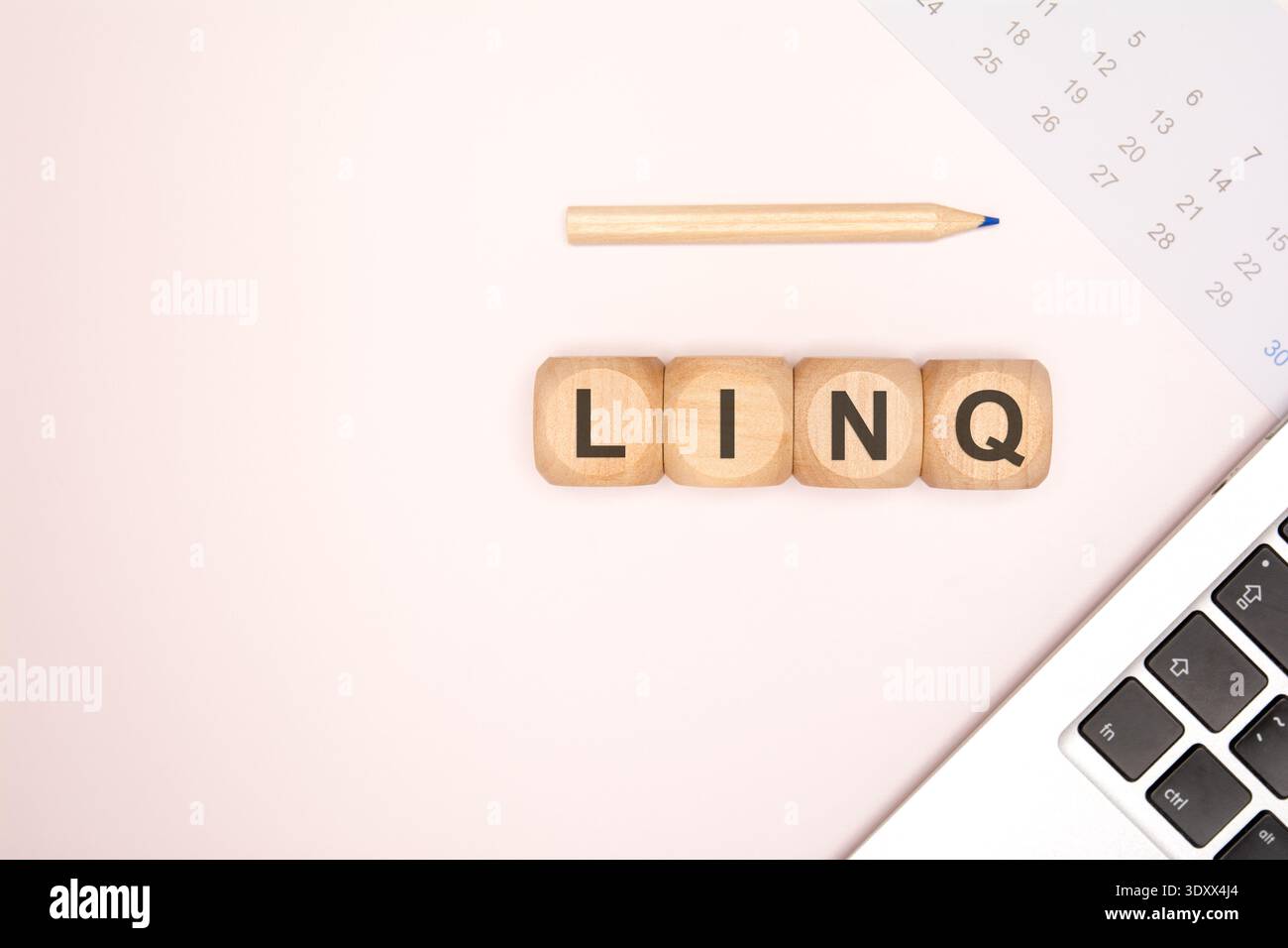 Vue de dessus de blocs de bois orthographiant l'acronyme LINQ sur une surface neutre légère avec un coin d'ordinateur portable, un crayon et un calendrier. Banque D'Images