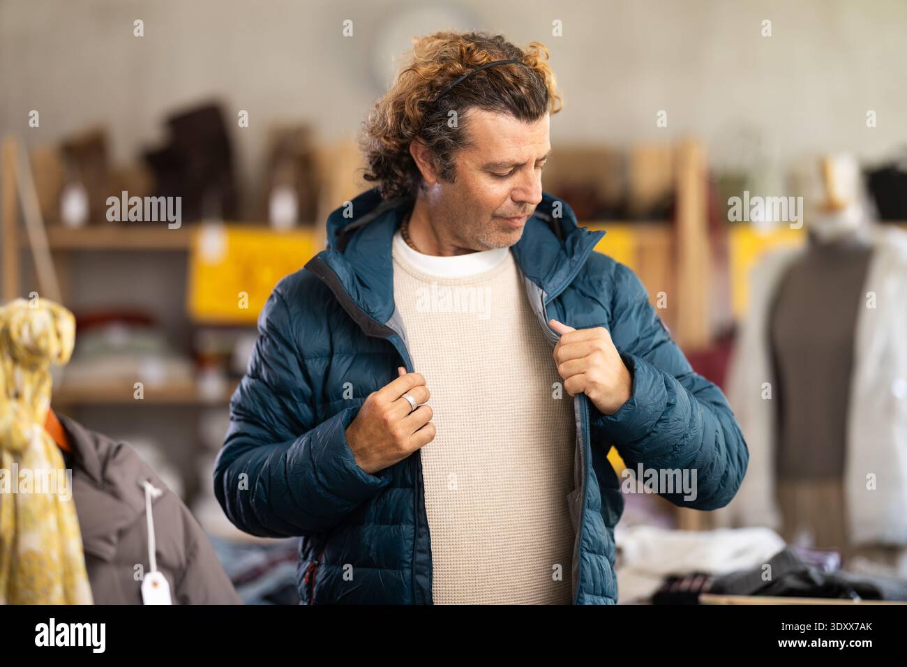 Homme élégant debout dans le magasin de vêtements et essayer une nouvelle veste en duvet Banque D'Images