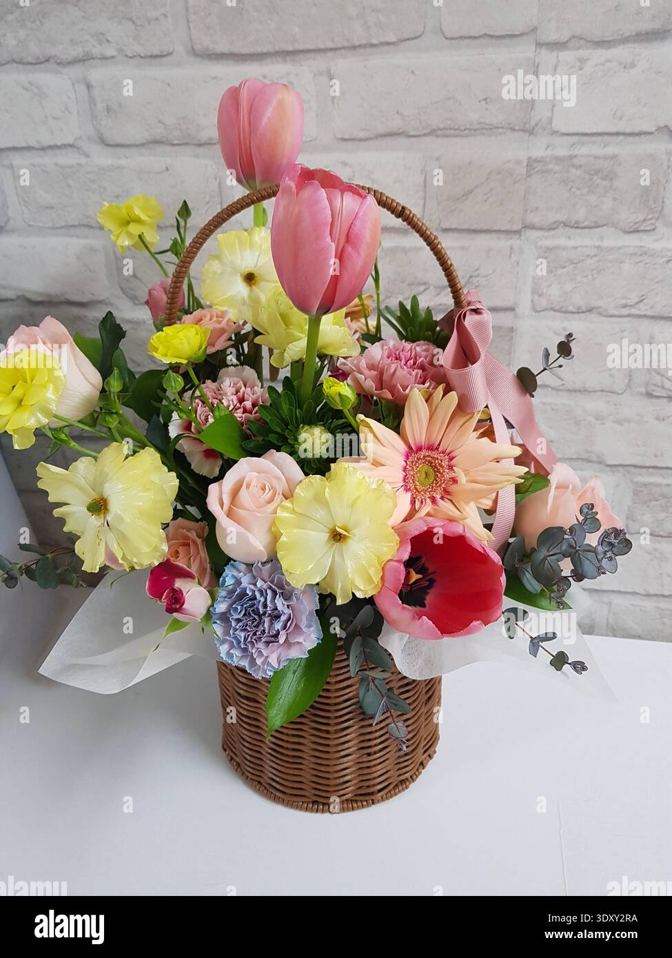 Arrangement de fleurs de printemps dans un panier en osier avec tulipes et roses Banque D'Images