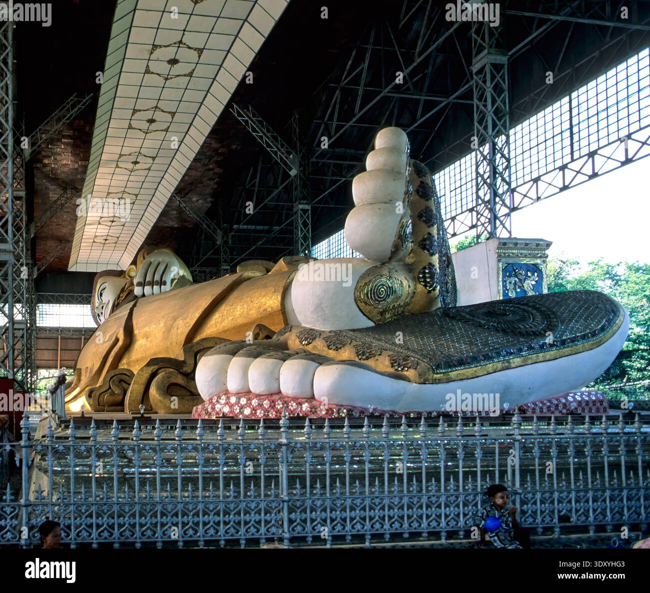 Les visiteurs explorent le Bouddha couché Shwetalyaung au Myanmar. La statue montre la figure de Bouddha reposant dans une grande salle. Banque D'Images