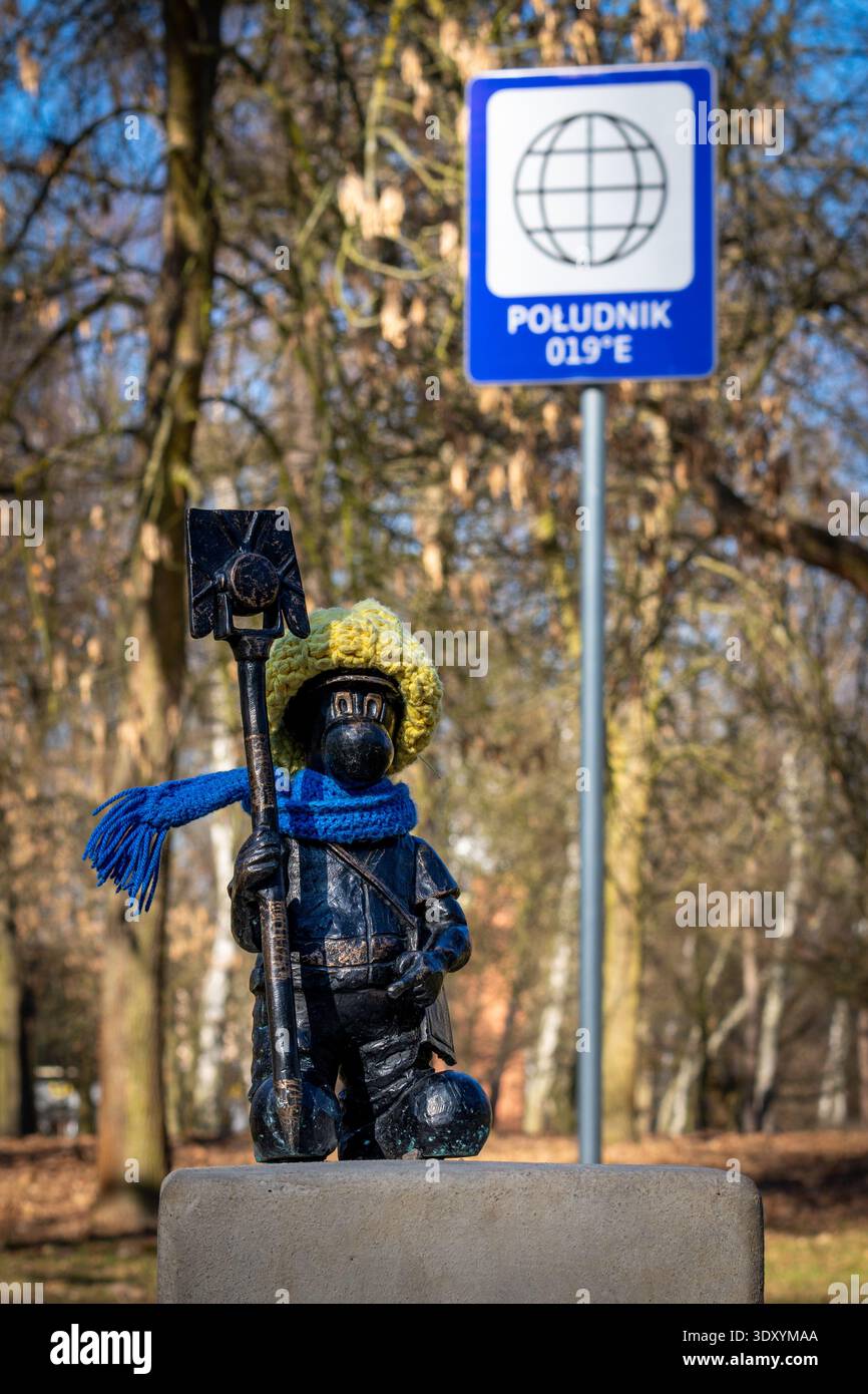 Plan vertical de la jolie statue de vache portant une écharpe bleue et un chapeau de laine jaune dans le parc Katowice Banque D'Images