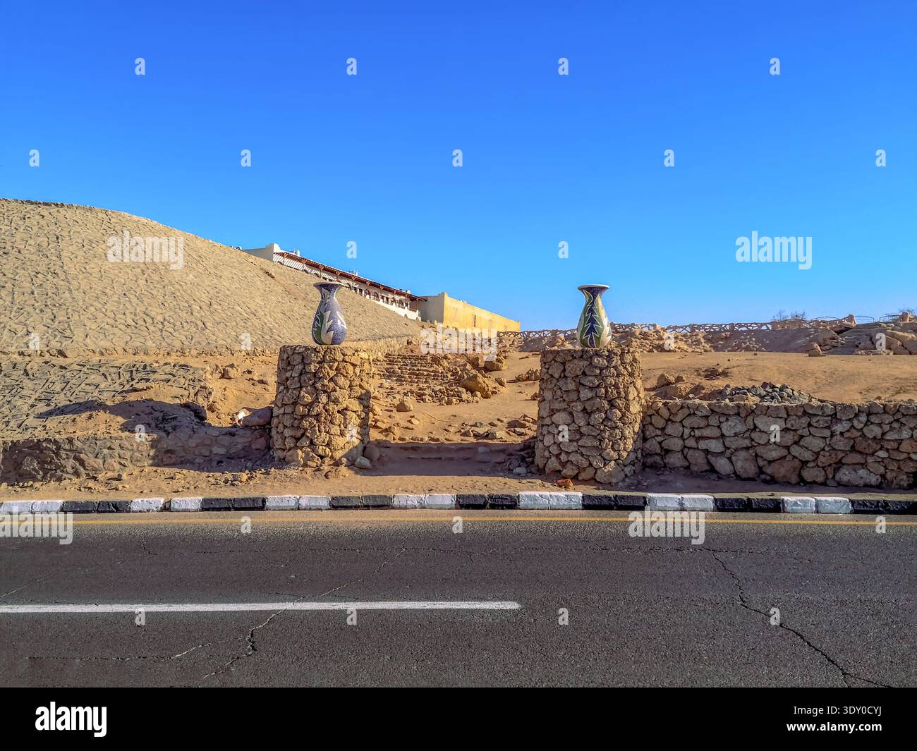 Deux nouveaux grands bols en céramique se dressent sur des piliers en pierre contre une friche avec des ruines. Paysage désertique exotique dans le vieux centre de Sharm El Sheikh - Image de stock capturée avec un smartphone