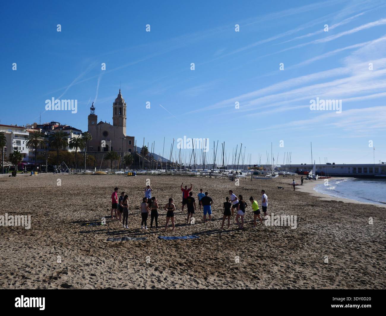 Les gens s'exercent ensemble dans un groupe sur la plage de Fragata en février. Style de vie de plage hivernale espagnole. Sitges, Espagne Banque D'Images