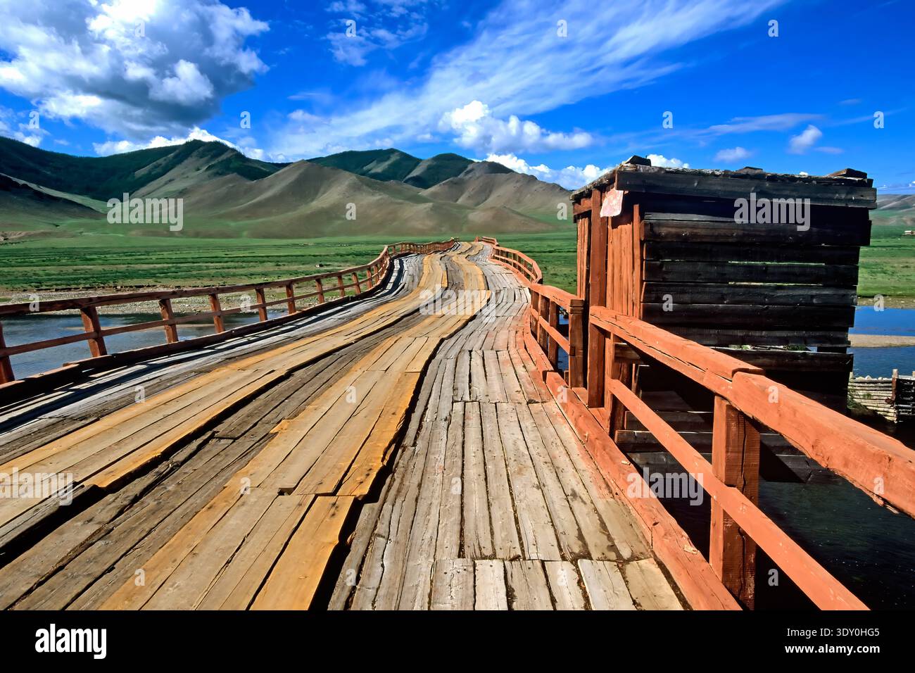 Un pont en bois s'étend sur la terre en Mongolie. Il se tient seul dans un large champ sous un ciel bleu avec des nuages. Banque D'Images