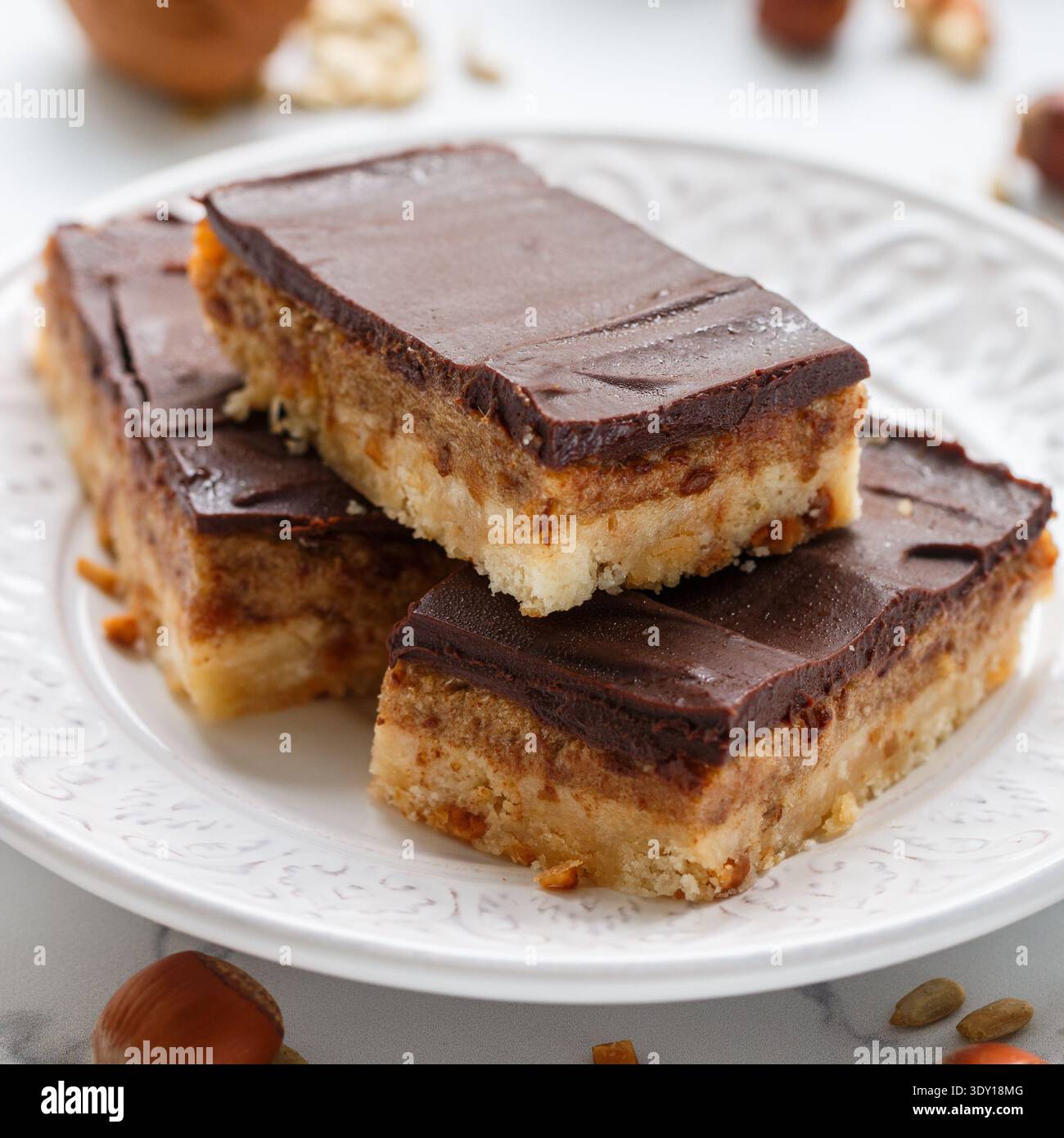 Le cacao végétalien maison date des barres de chocolat avec noix de coco, noisettes, noix et graines de tournesol sur fond blanc. Dessert sain. Le concept de Banque D'Images