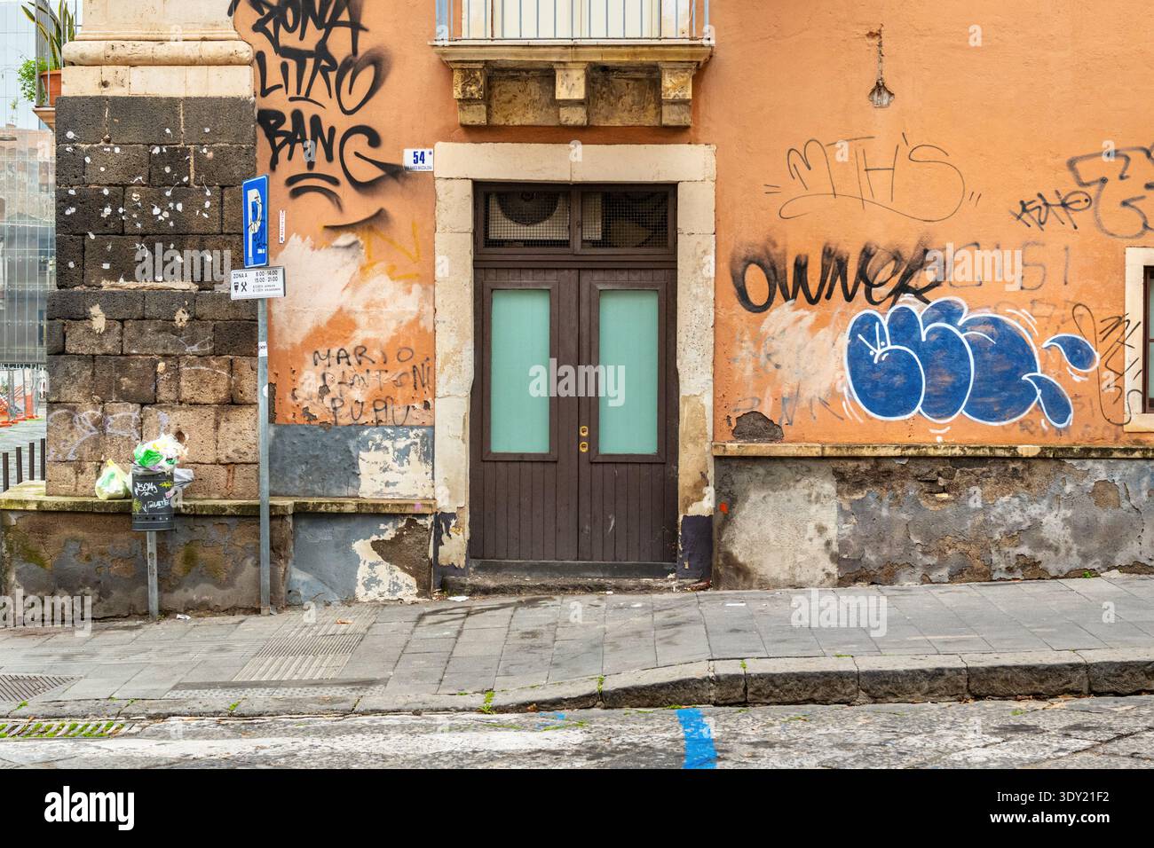 Une scène de rue en plein air dans la ville de Catane, Sicile, Italie. Une porte avec le mur couvert de graffitis non autorisés et rue peinte au spray Banque D'Images