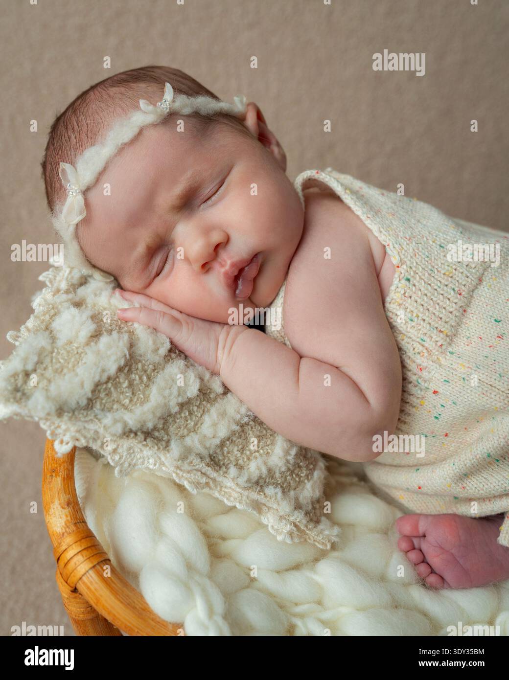 Portrait en gros plan d'une petite fille nouveau-née endormie reposant paisiblement sur un tissu tricoté doux. Tons neutres chauds et détails délicats Banque D'Images