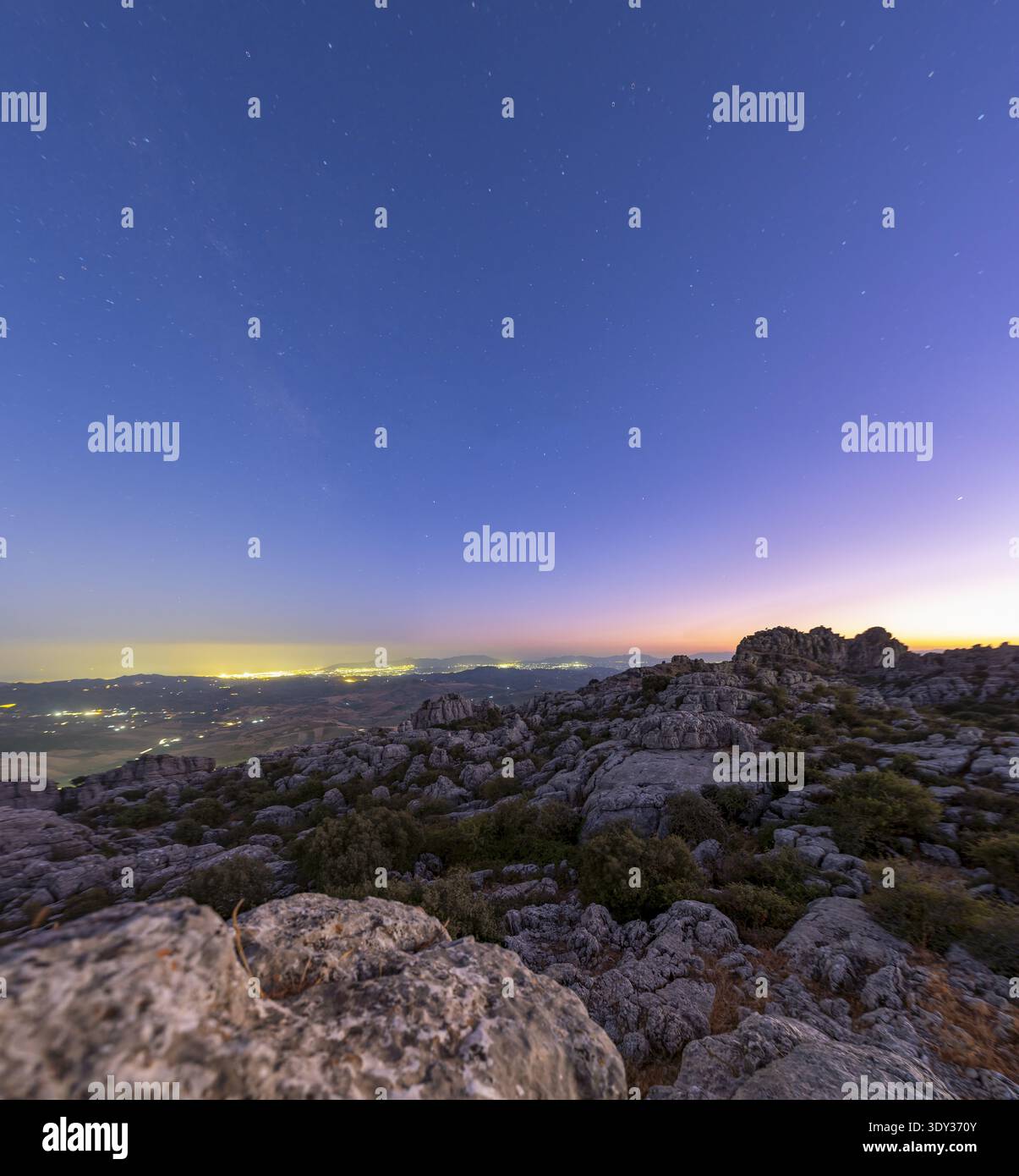 Vue panoramique sur le paysage karstique accidenté sous le ciel crépusculaire, avec des sentiers étoilés et un horizon lumineux de la région de Malaga Banque D'Images