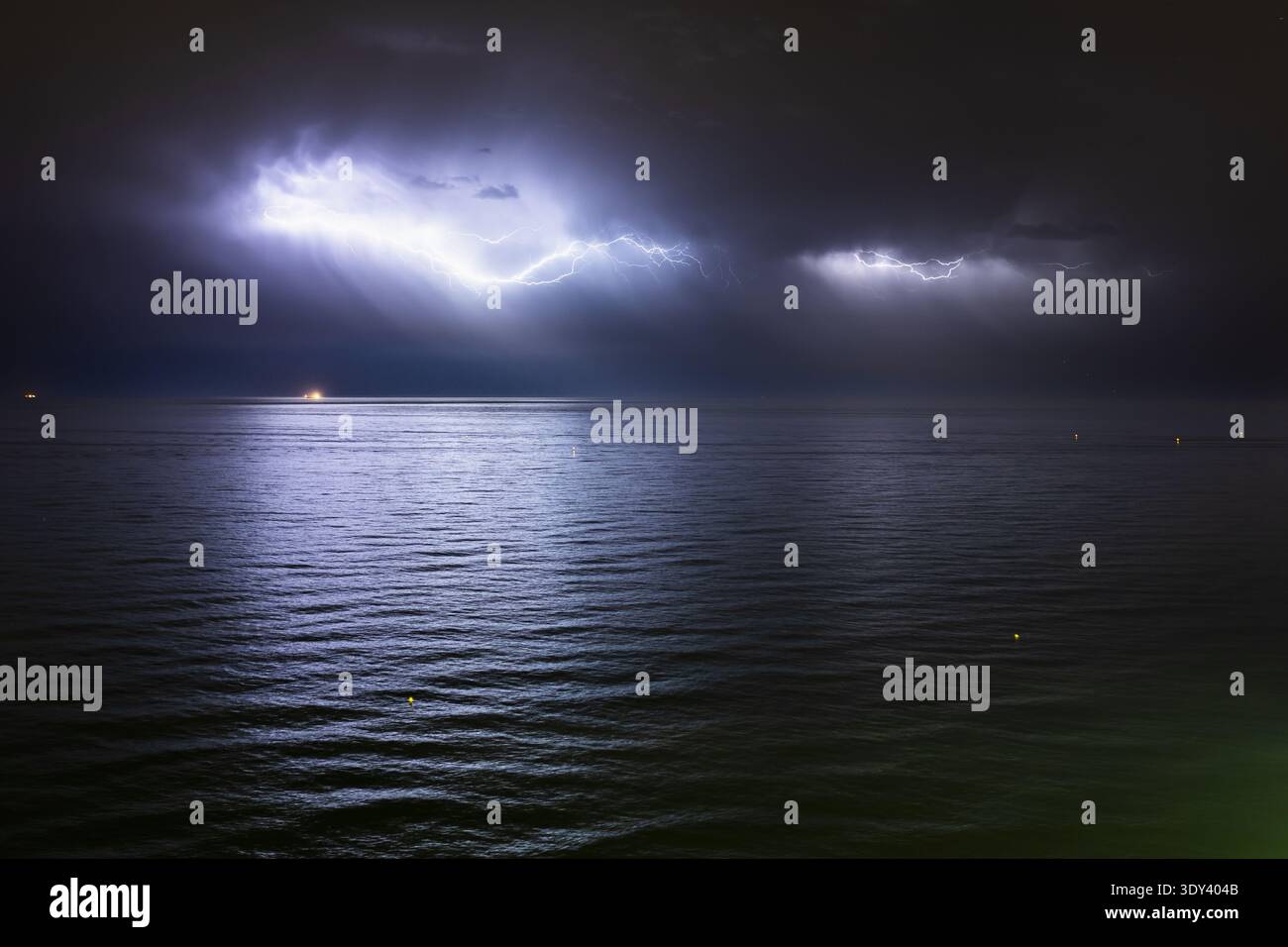 Orage nocturne sur la mer Méditerranée, avec des éclairs intenses à travers un ciel orageux reflétant sur la surface de l'océan Banque D'Images