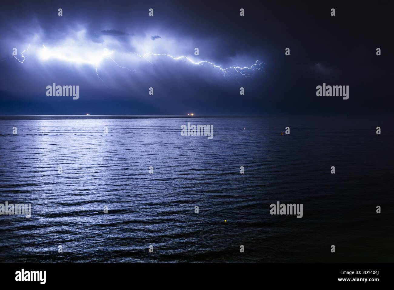 Orage nocturne spectaculaire sur la mer Méditerranée, avec des éclairs intenses à travers un ciel orageux reflétant sur la surface tranquille de l'océan Banque D'Images