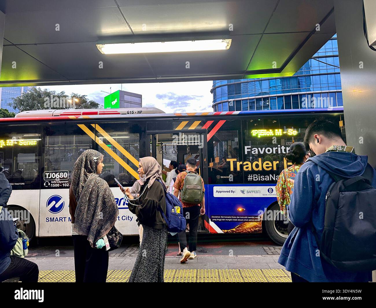 Jakarta - 5 mars 2026 : les navetteurs munis de sacs à dos et de smartphones montent à bord d'un bus urbain à un arrêt animé pendant l'heure de pointe du soir dans le centre de Jakarta. - Image de stock capturée avec un smartphone