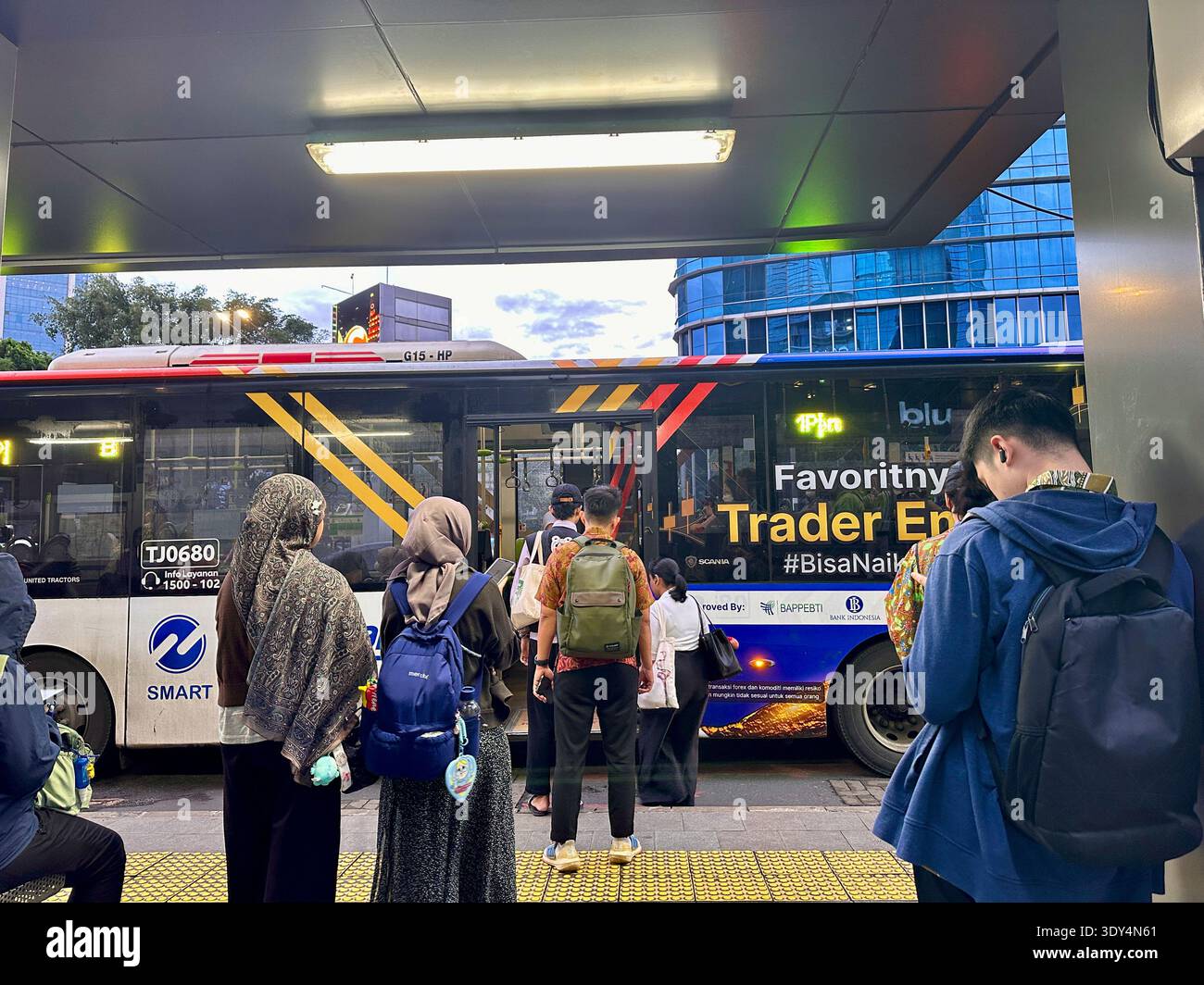 Jakarta - 5 mars 2026 : les navetteurs munis de sacs à dos et de smartphones montent à bord d'un bus urbain à un arrêt animé pendant l'heure de pointe du soir dans le centre de Jakarta. - Image de stock capturée avec un smartphone