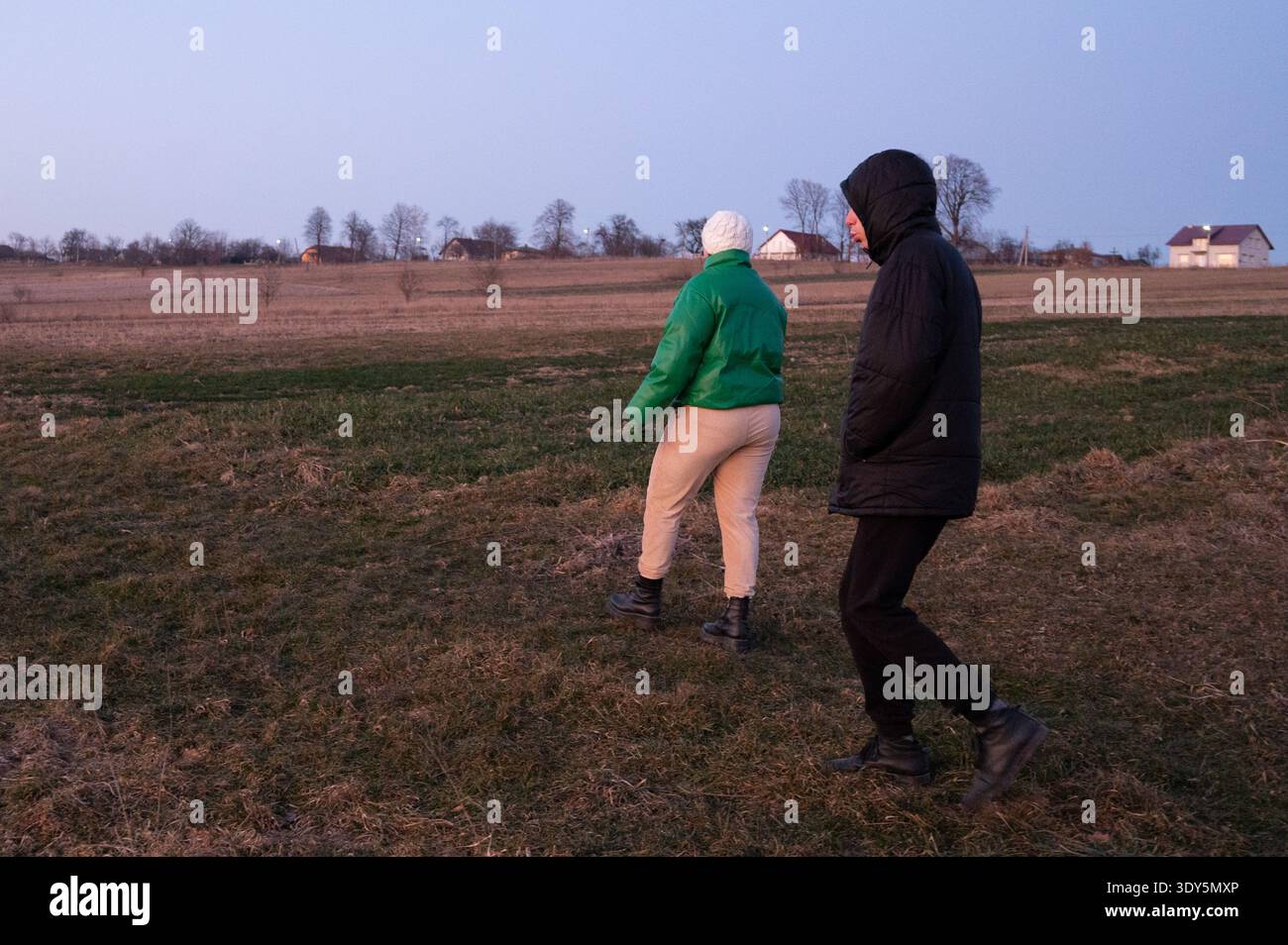 Couple se promène dans la campagne tranquille au crépuscule, embrassant les moments tranquilles que la journée passe à la nuit et les teintes douces du crépuscule remplissent Banque D'Images