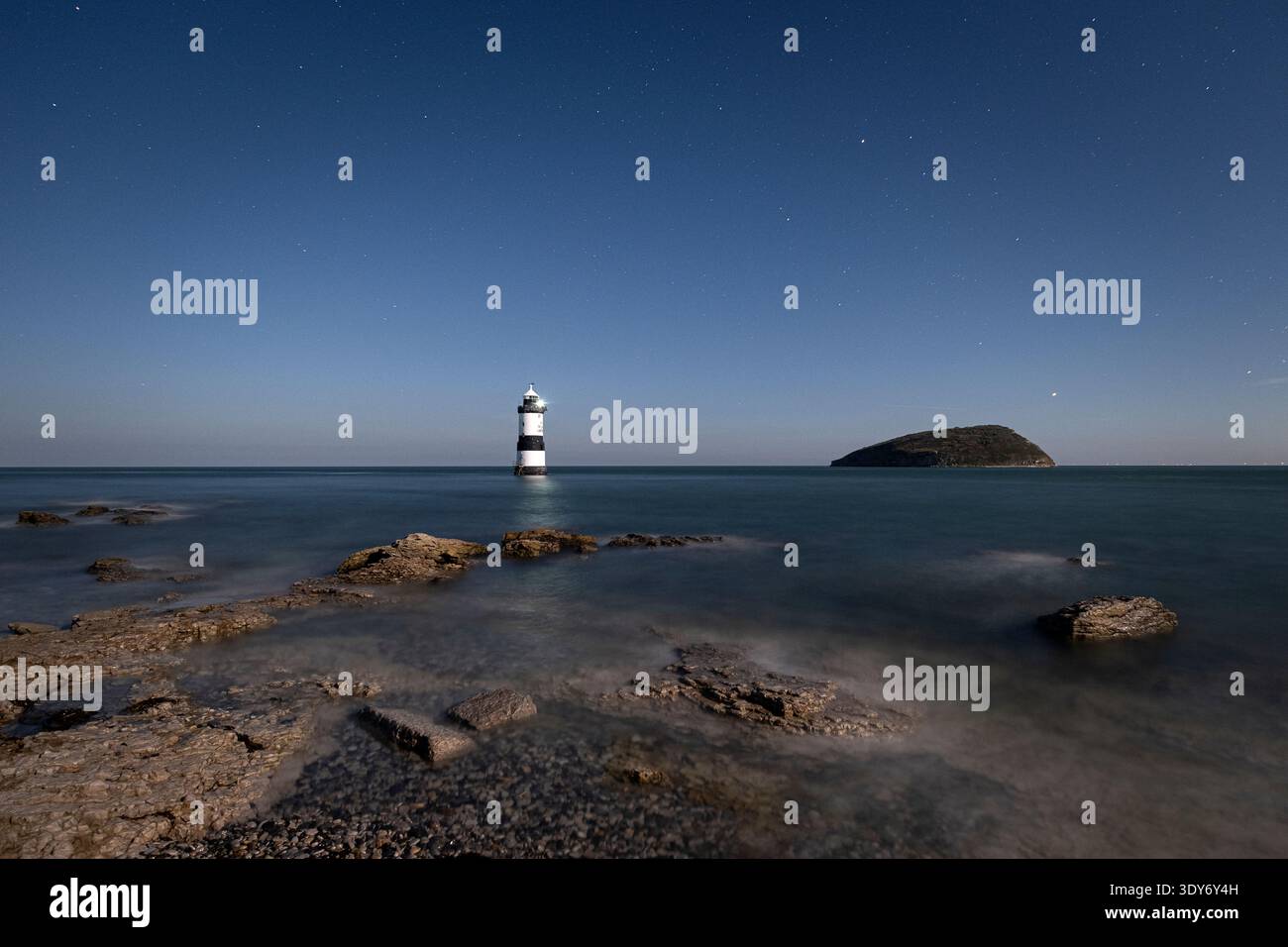 Le ciel nocturne brille au-dessus du phare de Trwyn du à Penmon point sur l'île d'Anglesey dans le nord du pays de Galles Banque D'Images