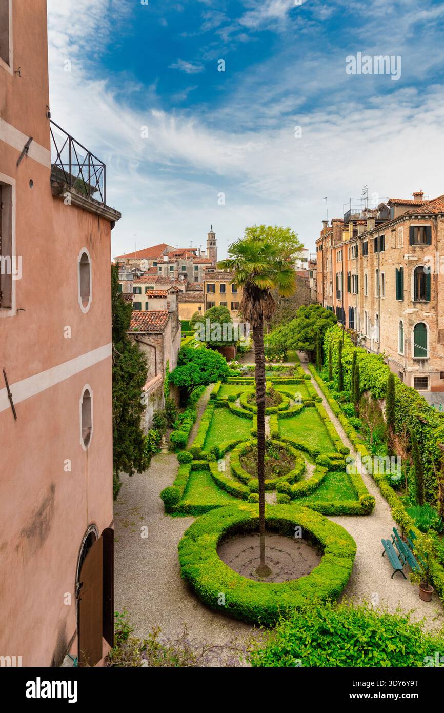 Explorez le jardin verdoyant du Palazzo Nani Bernardo sur canal Grande, Venise, avec vue sur les bâtiments historiques et un ciel dégagé Banque D'Images