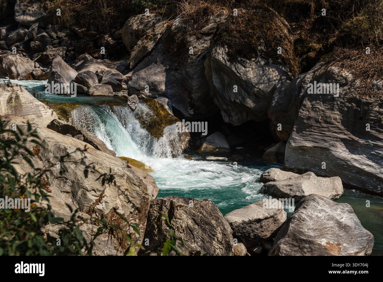 La rivière turquoise coule sur des rochers lisses dans les montagnes de Langtang Valley, au Népal avec une végétation sèche autour Banque D'Images