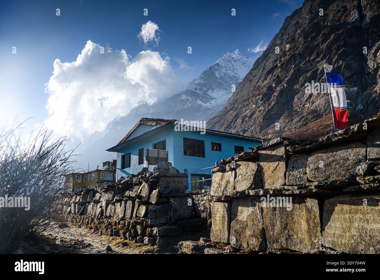 Salon de thé bleu et drapeaux de prière le long de la route de trekking dans la vallée de Langtang avec des nuages dans le ciel Banque D'Images