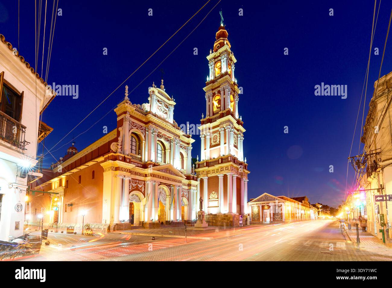 Des pistes de voiture éclairent une route vide au crépuscule près de l'église Saint François à Salta, Argentine Banque D'Images