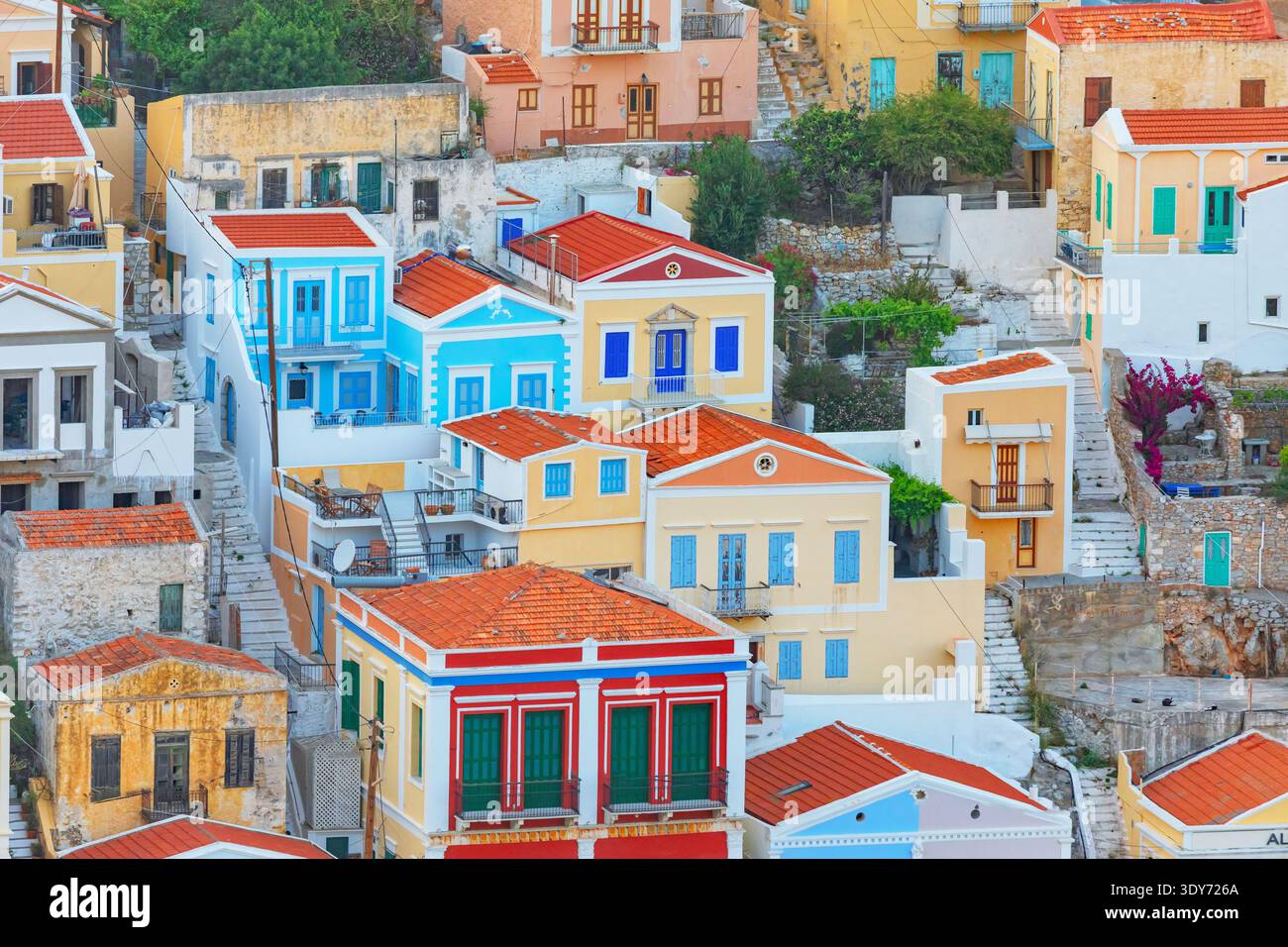 Des maisons colorées se dressent à Gialos sur l'île de Symi en Grèce avec des toits lumineux et des murs vibrants sous un ciel clair Banque D'Images