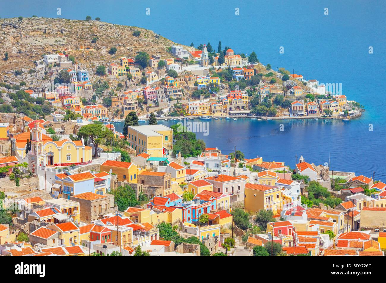 Vue en angle élevé du port de Gialos sur l'île de Symi en Grèce avec des maisons colorées et une mer bleue claire Banque D'Images