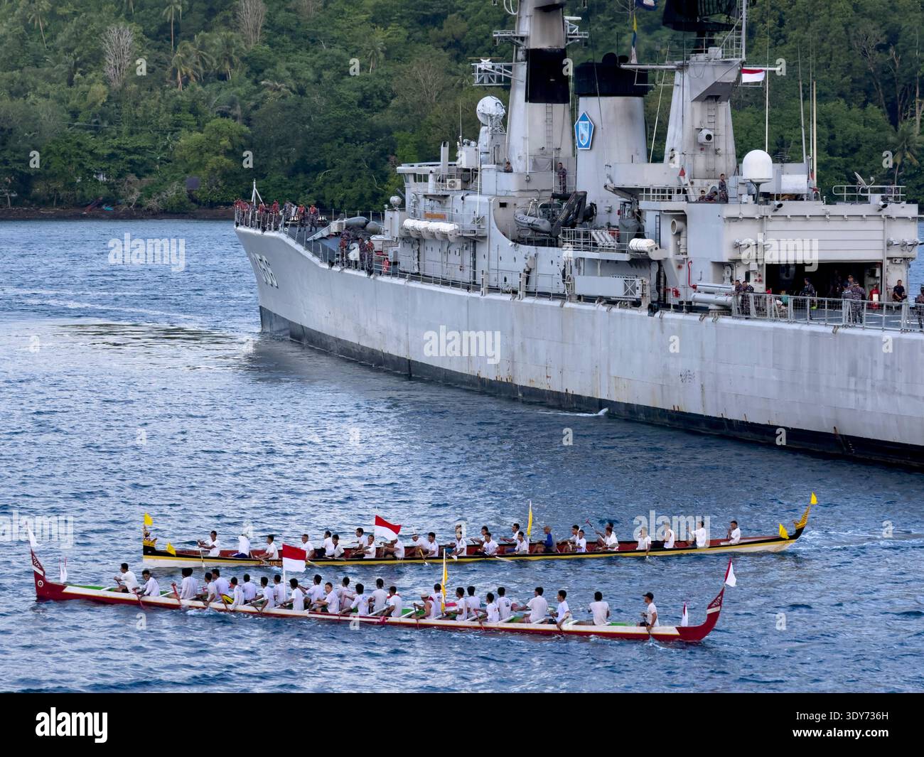 Des groupes de rameurs accueillent un navire de visite à Banda Neira avec des bateaux traditionnels et des drapeaux dans les Moluques, en Indonésie Banque D'Images