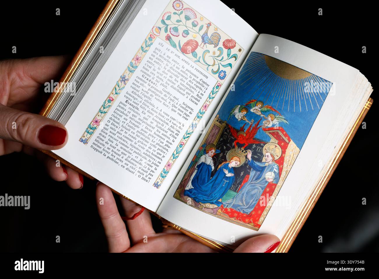 Une femme catholique lit le missel illustré du couronnement de la Vierge dans le ciel en France Banque D'Images