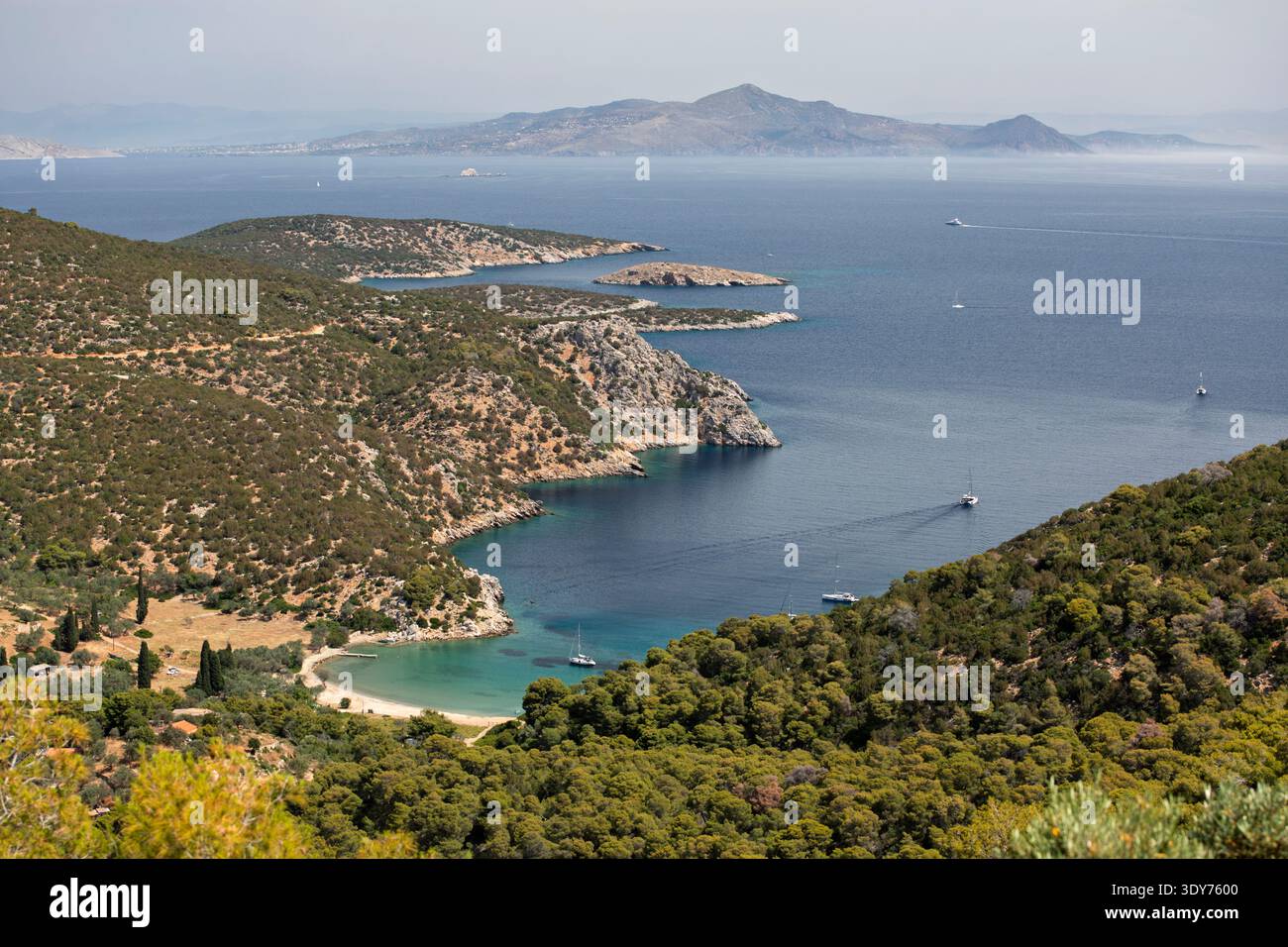 La plage de Vagionia Bay offre une vue sur les collines verdoyantes et les eaux bleues de Poros, en Grèce, soulignant la beauté des îles Saroniques en Europe Banque D'Images