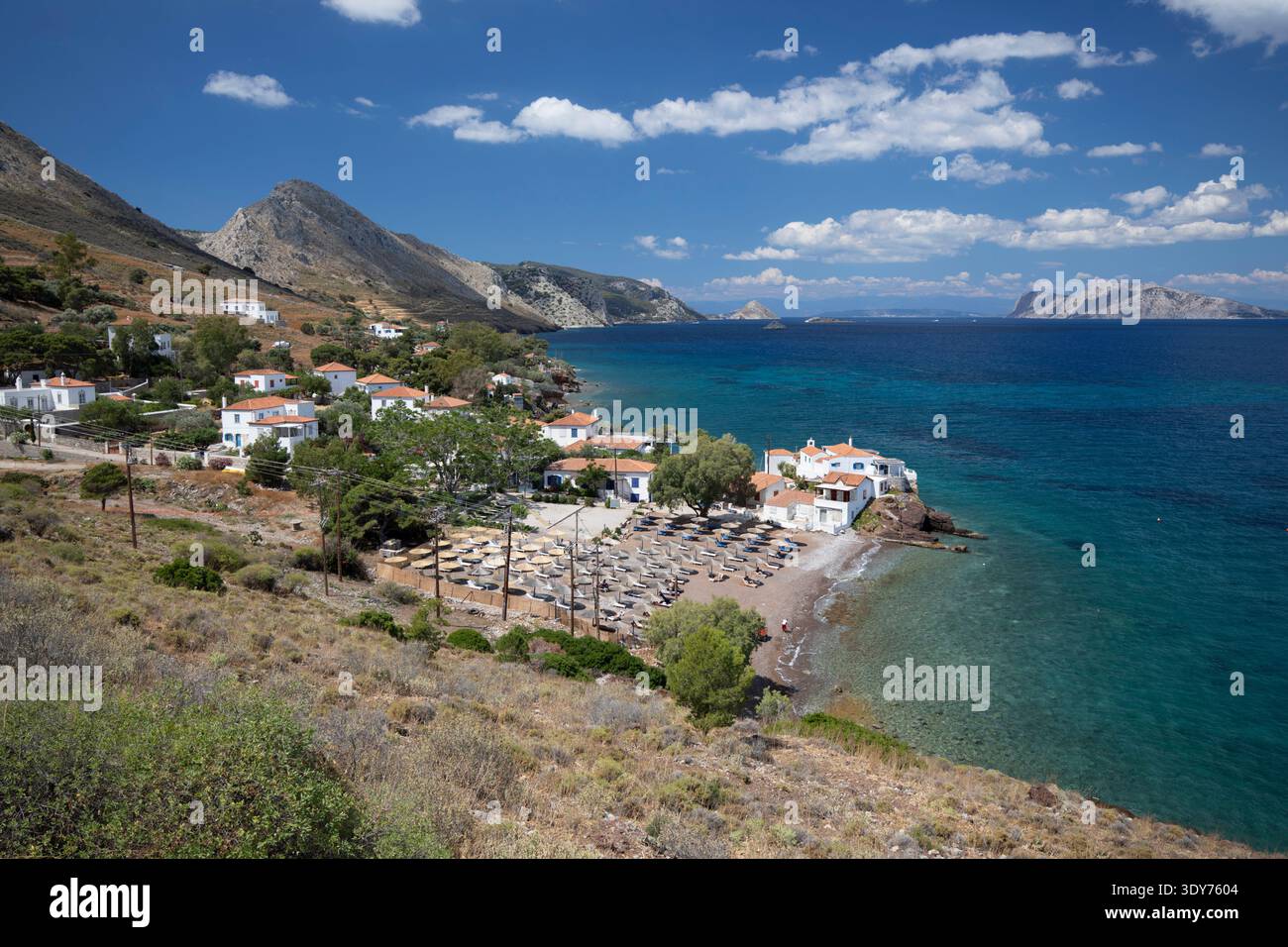 Les visiteurs profitent de la journée ensoleillée à la plage de Vlychos à Hydra, entourée de montagnes et d'eaux claires en Grèce Banque D'Images