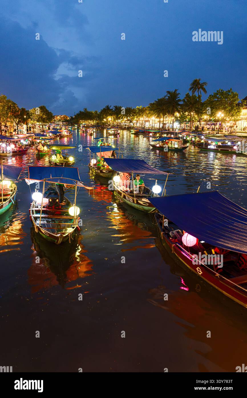 Les bateaux flottent sur la rivière Thu bon au crépuscule avec des lumières dans la vieille ville de Hoi an, reflétant la culture locale et la vie quotidienne au Vietnam Banque D'Images