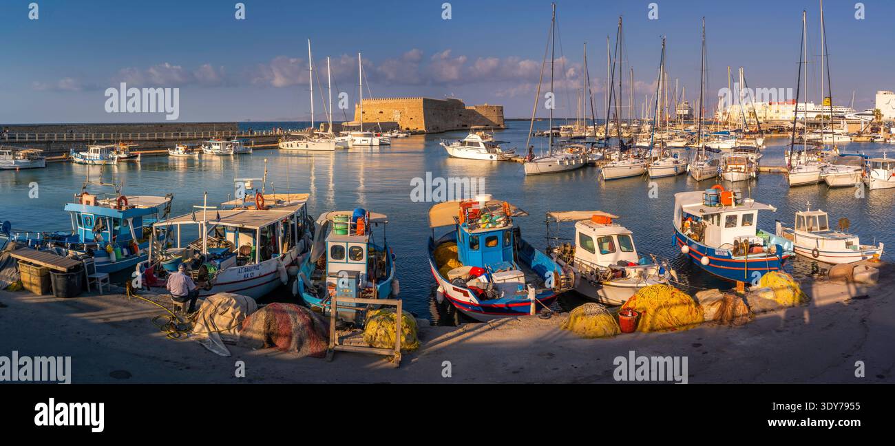 Vue sur le coucher du soleil de la forteresse vénitienne de Koules et des bateaux dans le port d'Héraklion en Crète, Grèce Banque D'Images