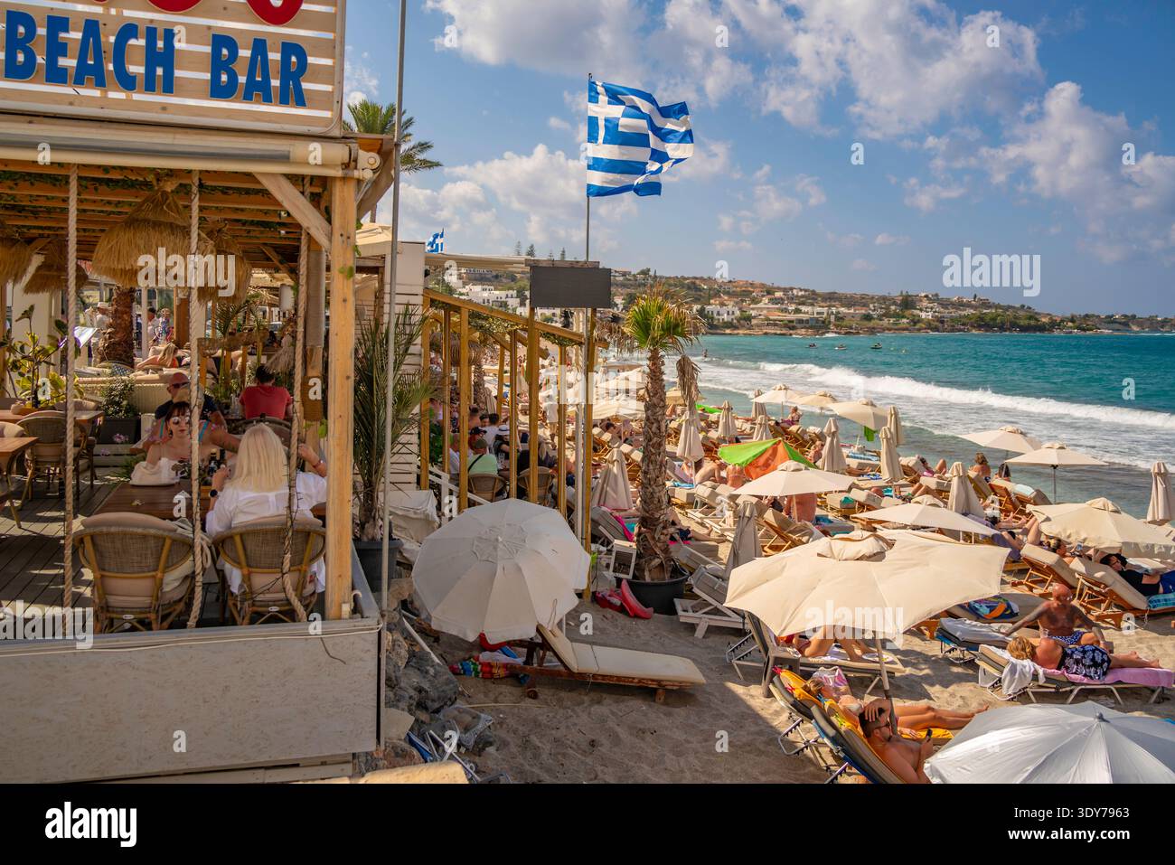 Les visiteurs se détendent et profitent du soleil à la plage Akti Navarchou Nearchou à Limenas Chersonisou, en Crète pendant une journée bien remplie en Grèce Banque D'Images