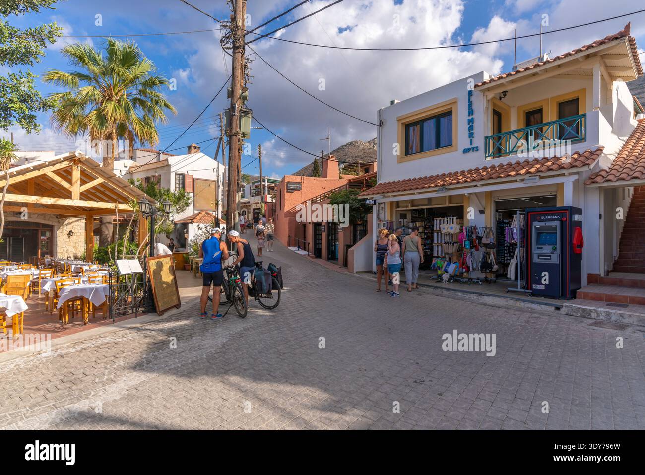 Les visiteurs explorent les boutiques et les tavernes à Koutouloufari, en Crète, par une journée ensoleillée dans un village pittoresque de Grèce Banque D'Images