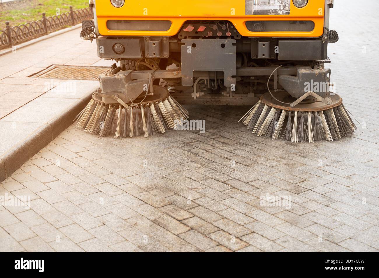 Véhicule moderne de nettoyage des rues avec brosses rotatives travaillant dans une zone urbaine. Concept d'entretien technologique de la ville, service d'utilité publique, et Banque D'Images