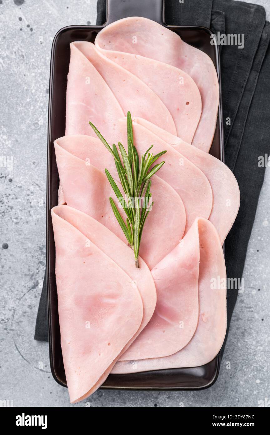 Jambon tranché gourmand sur une planche rustique, vous invitant à explorer de délicieuses recettes et de délicieuses associations. fond gris. vue de dessus. Banque D'Images