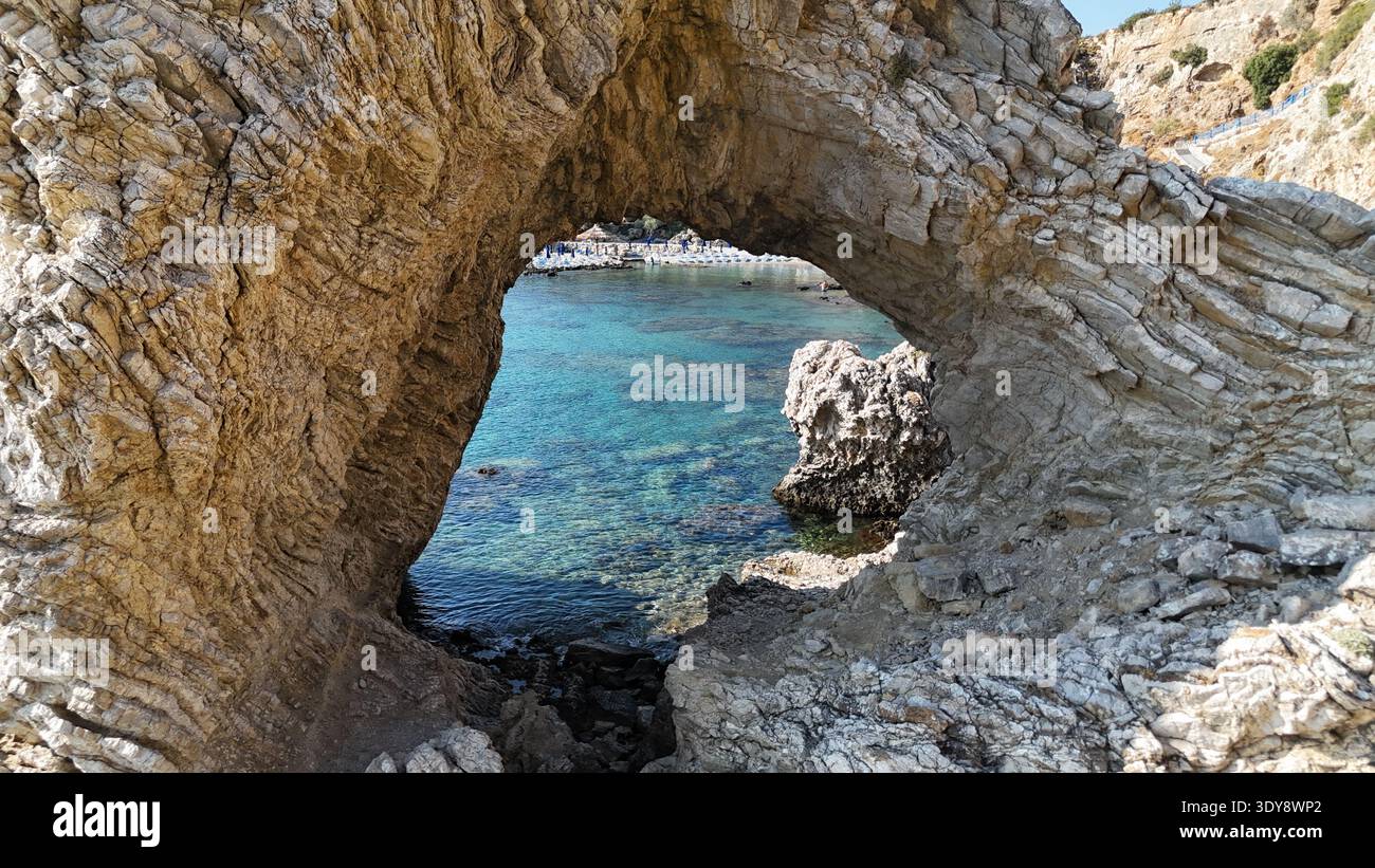 Arc de roche naturel encadrant la crique méditerranéenne sur l'île de Rhodes Grèce Banque D'Images
