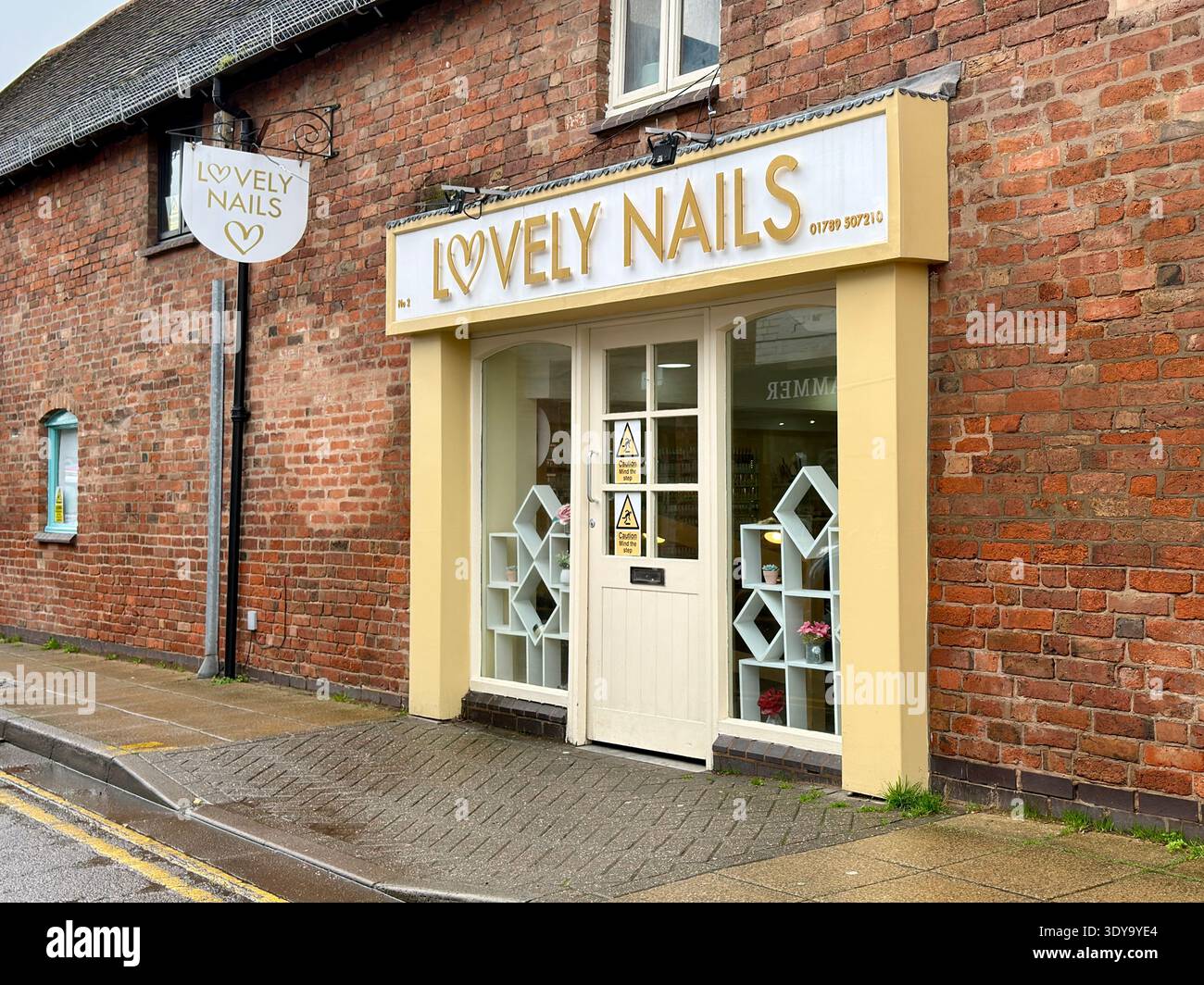 Extérieur du salon de manucure « Lovely Nails » à Stratford-upon-Avon, Royaume-Uni, montrant une façade jaune, un bâtiment en briques et une entrée. Banque D'Images