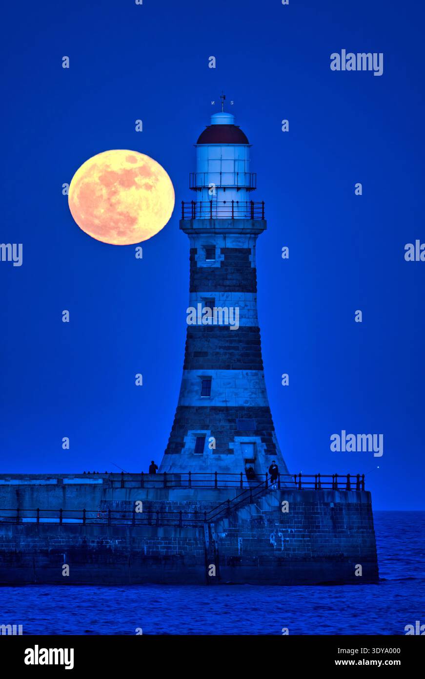 Une vue au crépuscule de la pleine lune de mars vers un ciel clair au-dessus de Roker Pier et phare à Sunderland, Tyne & Wear Banque D'Images