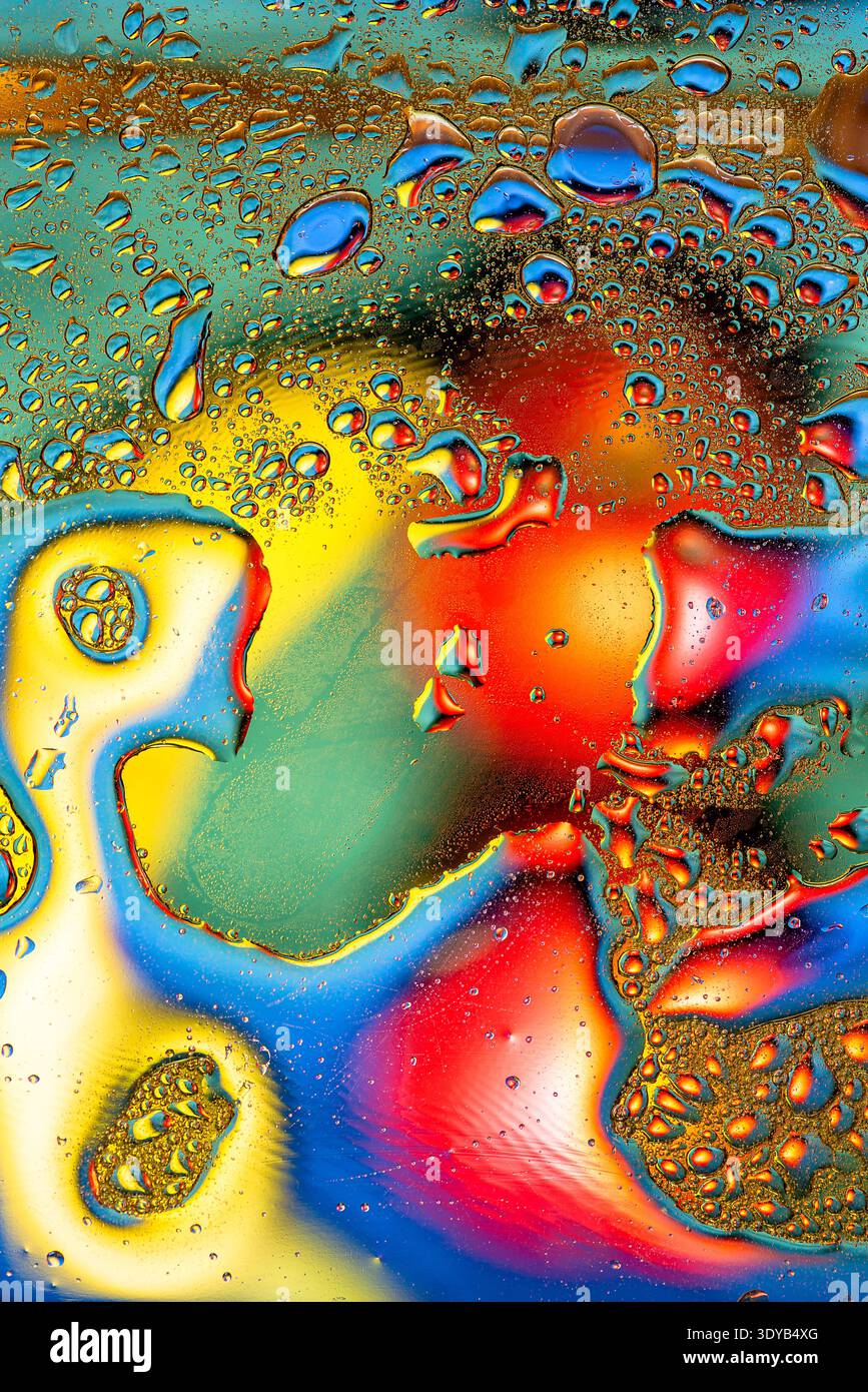 Gros plan artistique d'un film d'huile sur l'eau reflétant un spectre complet de couleurs arc-en-ciel avec de grandes formes fluides et de minuscules détails de bulle. Banque D'Images
