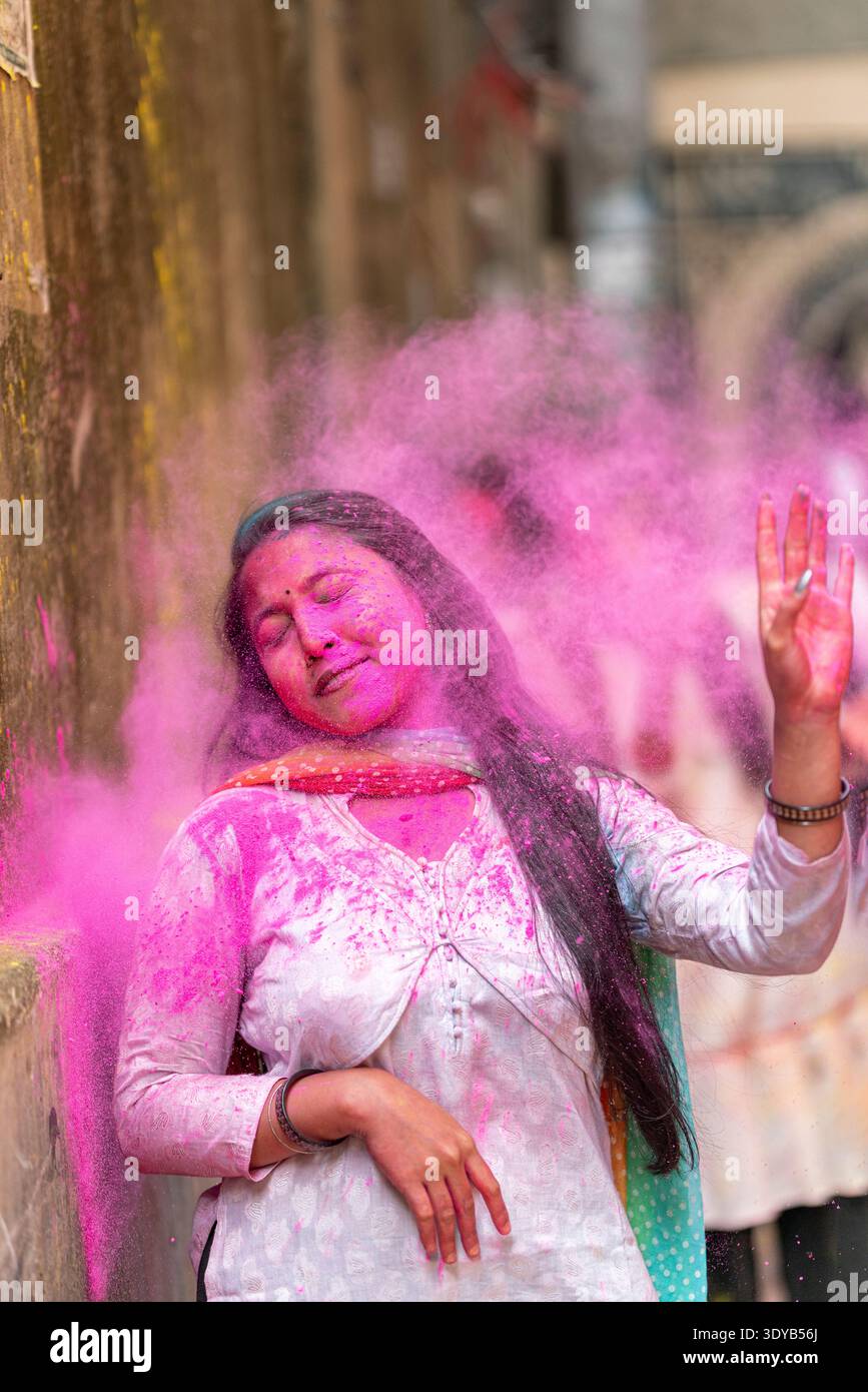 Femme joyeuse célébrant Holi Festival avec de la poudre rose. Holi au Bangladesh est un beau mélange de dévotion spirituelle et d'harmonie culturelle Banque D'Images