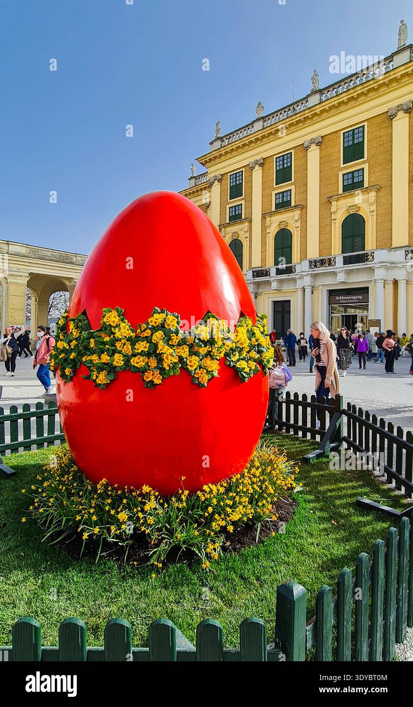 Vienne, Autriche - 30 mars 2024 : œuf de pâques rouge géant avec givrage jaune au Palais impérial de Schnobrunn Banque D'Images